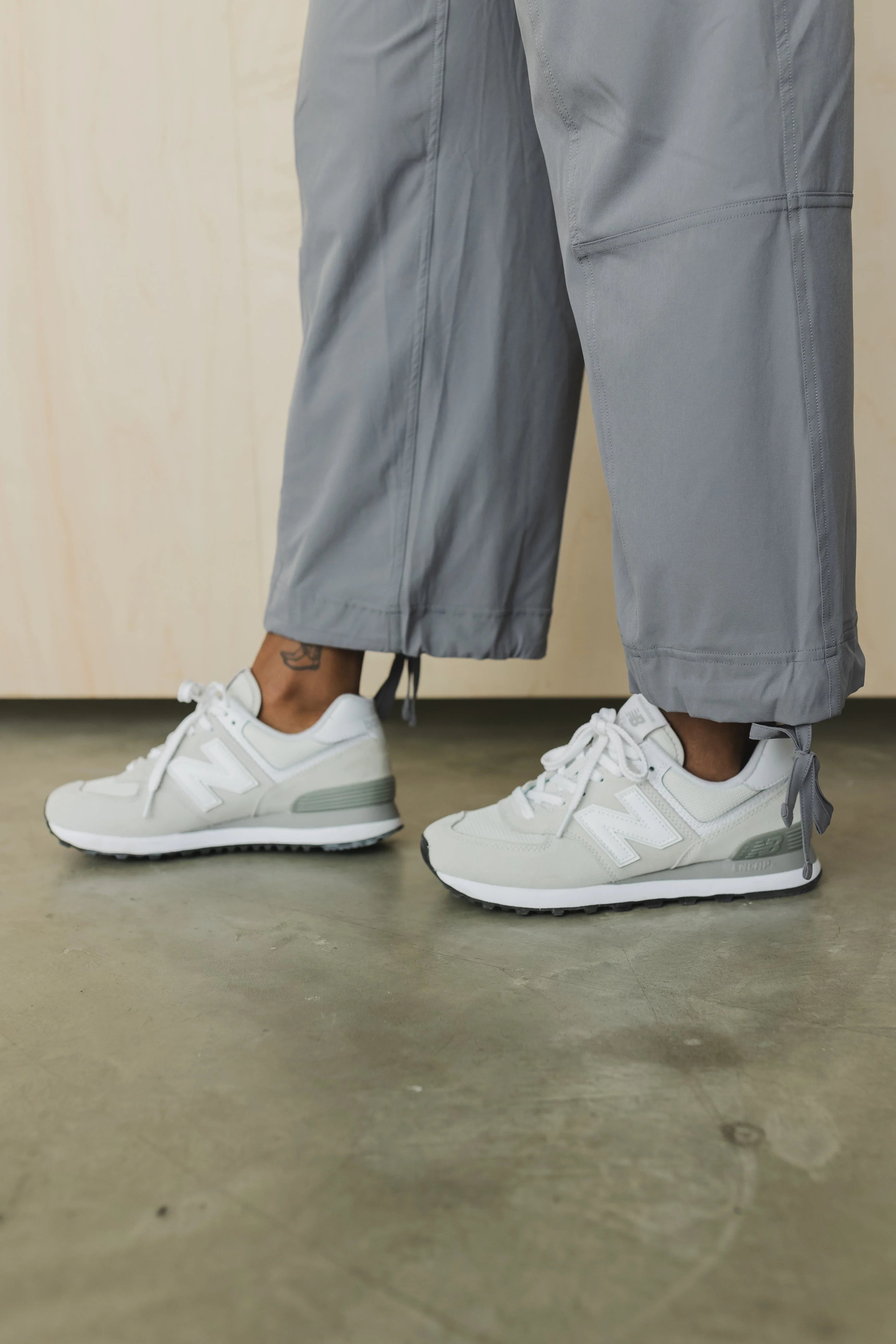 Person wearing grey New Balance sneakers and light grey pants on a concrete floor