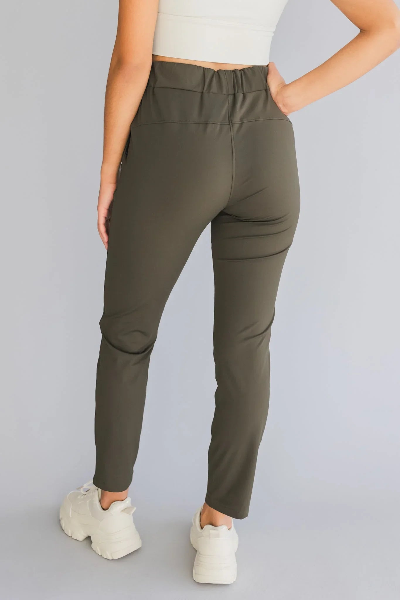 Back view of woman in olive green high-waisted pants and white sneakers