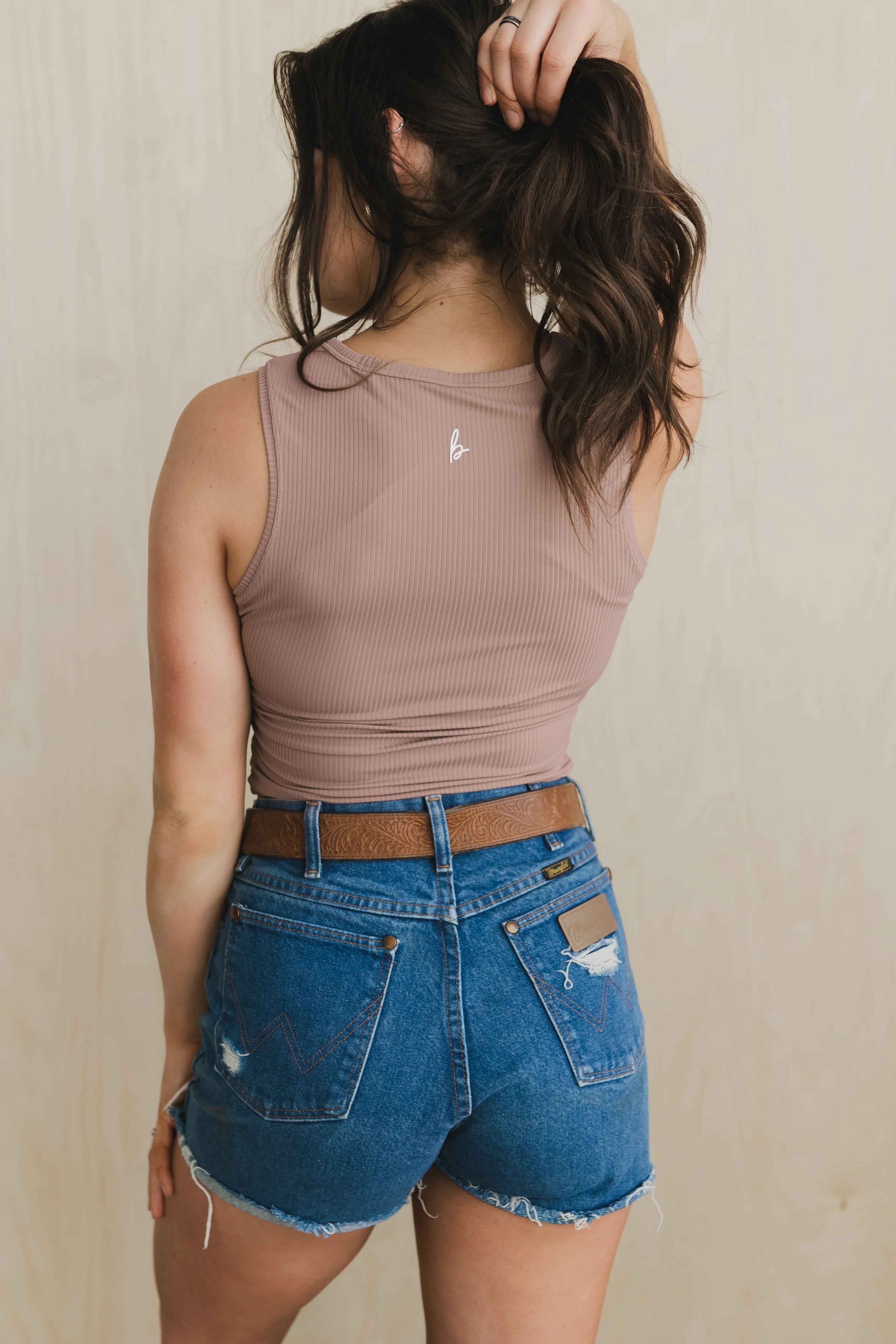 Woman in mauve ribbed crop tank and high-waisted distressed denim shorts