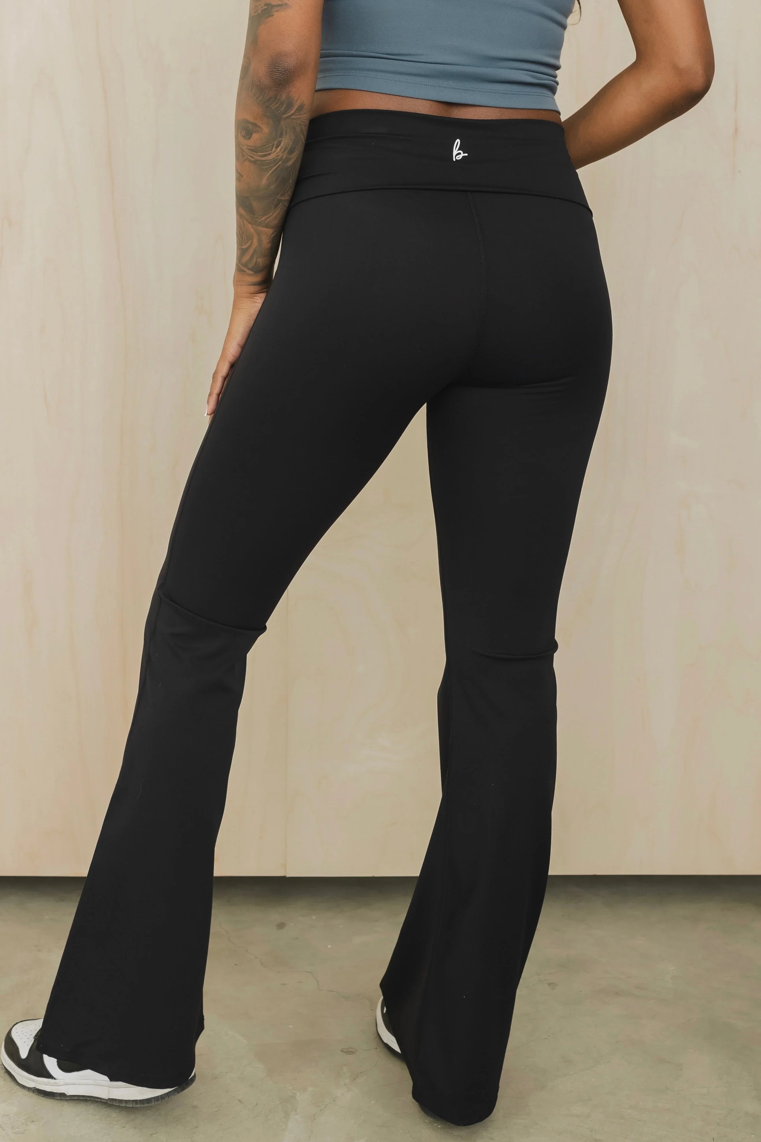 Woman wearing black high-waisted flare yoga pants and sneakers, back view
