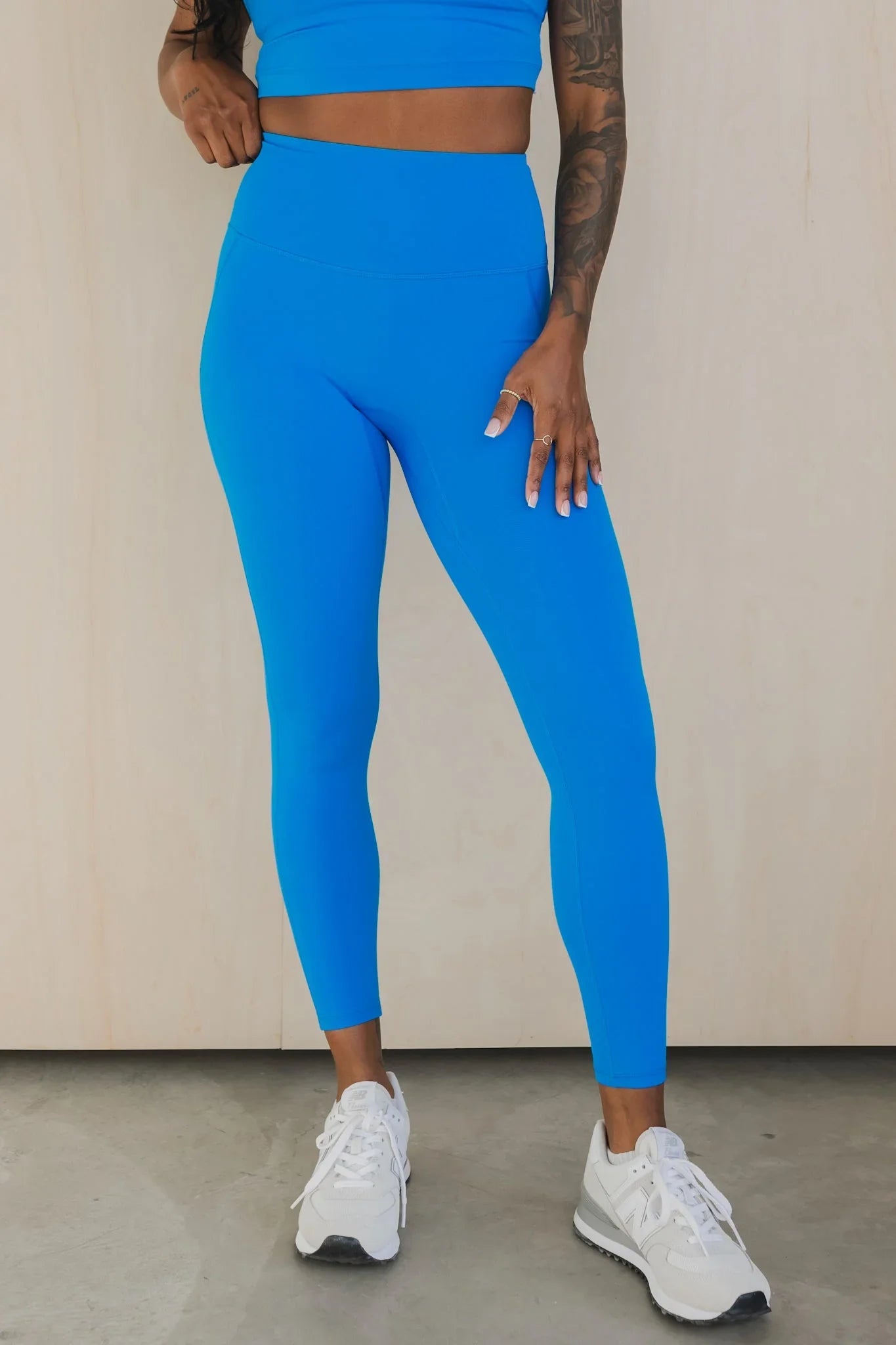 Woman wearing bright blue high-waisted leggings and crop top with white sneakers