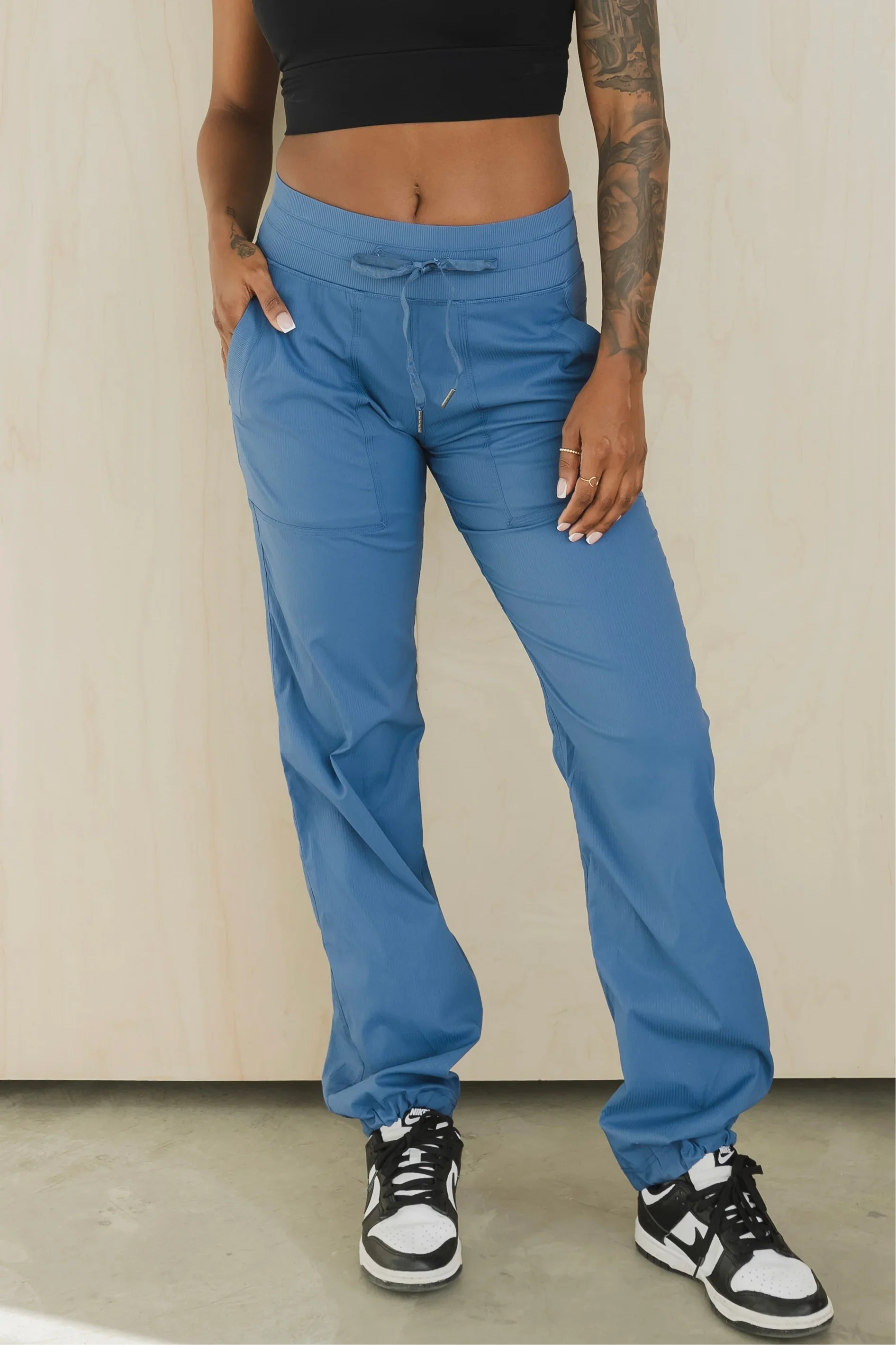 Blue jogger scrub pants with drawstring waist on woman, black crop top, Nike sneakers