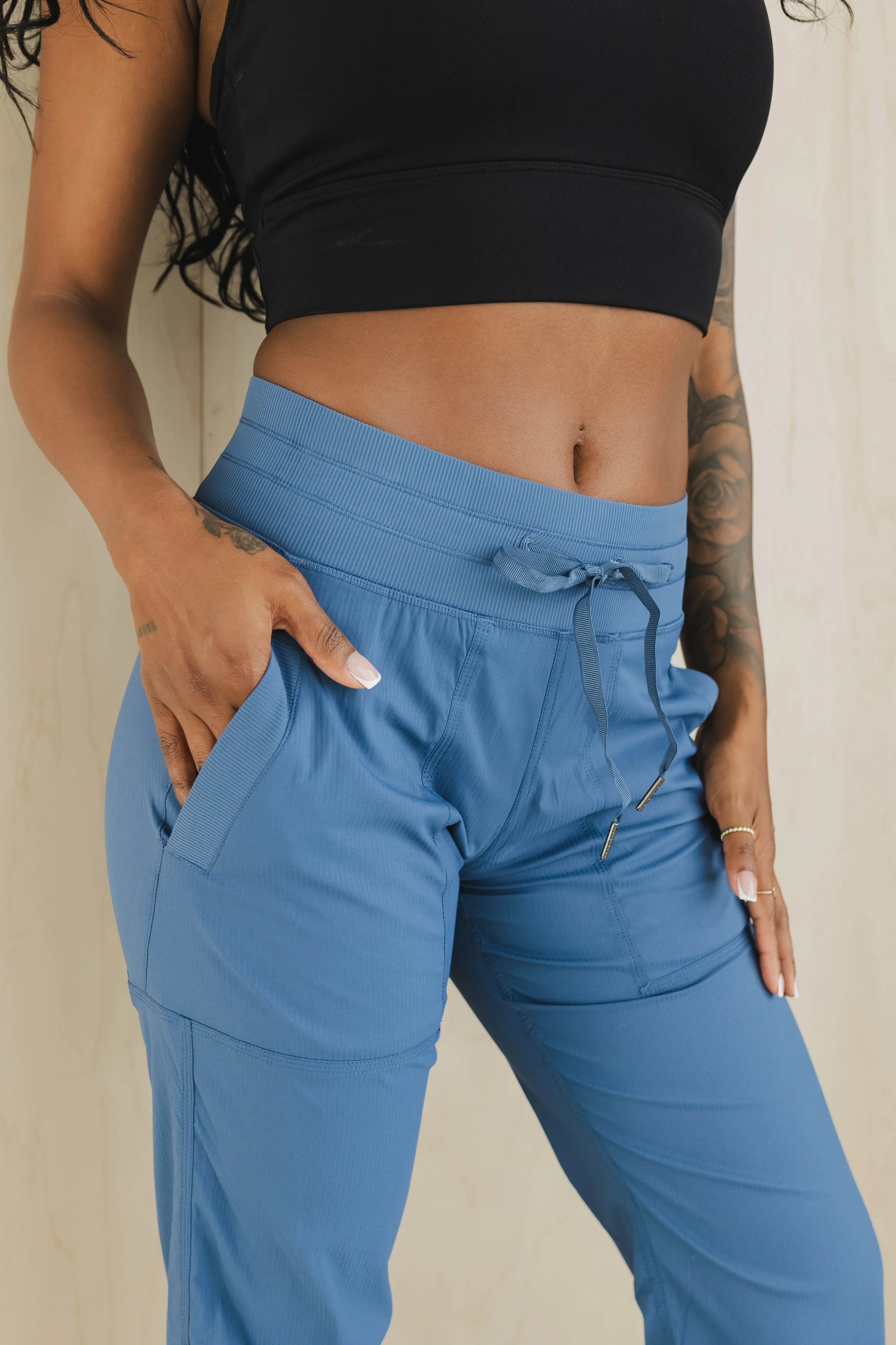 Woman wearing high-waisted blue jogger pants with drawstring and side pockets