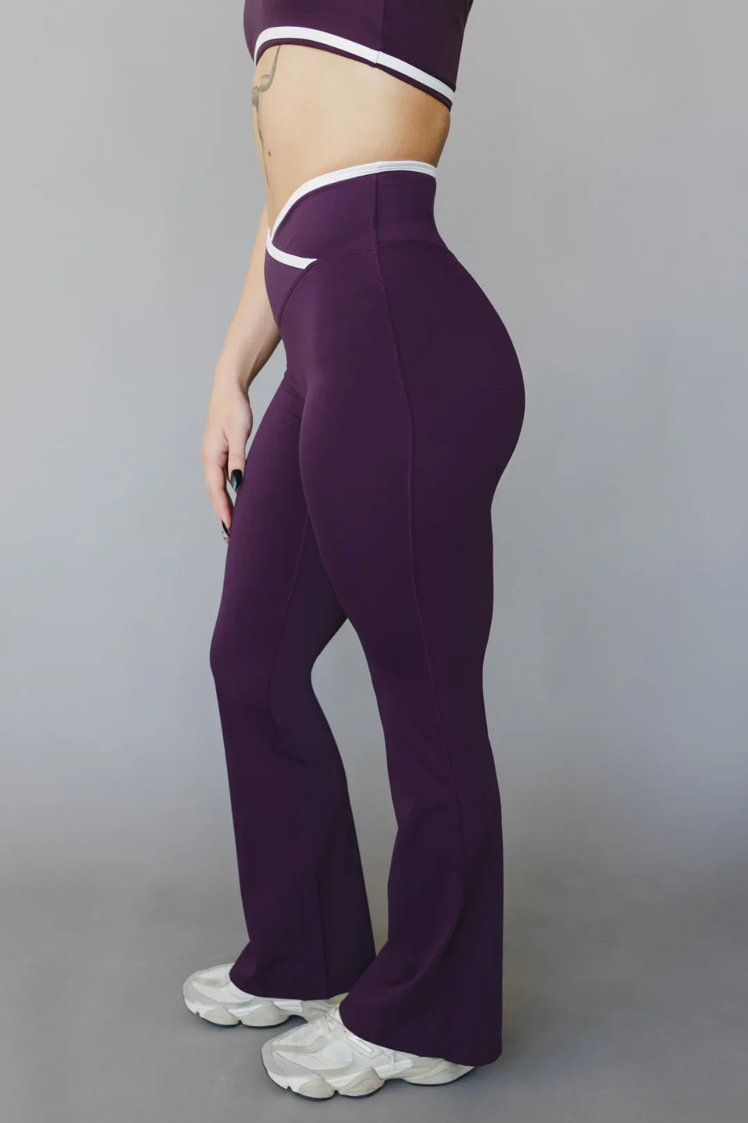 Woman wearing high-waisted purple flared leggings and matching crop top, side view