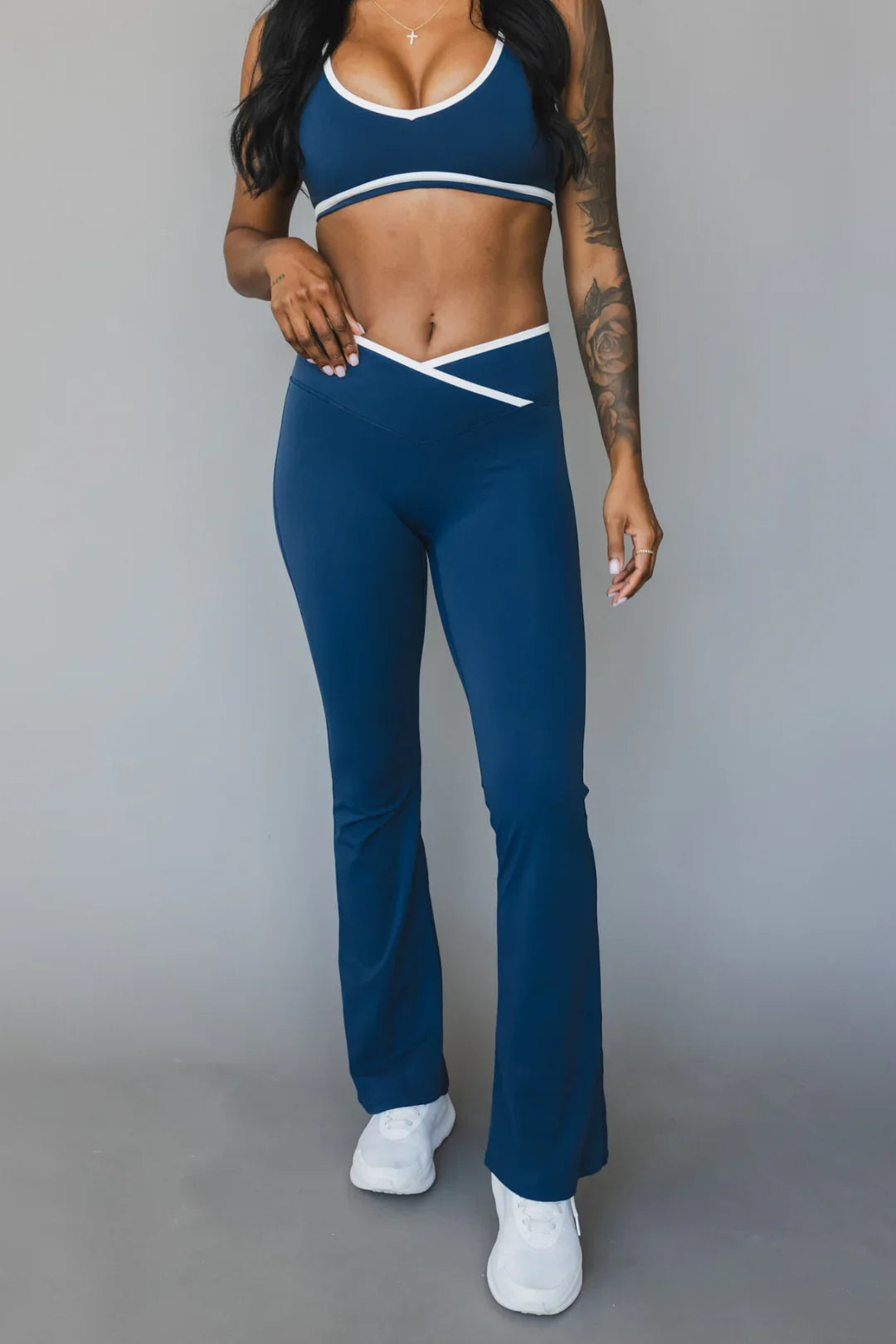Woman in blue two-piece workout set with white trim, flared pants, and white sneakers