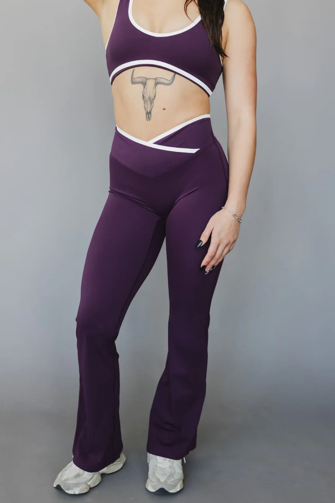 Woman in purple workout set with white trim, high-waisted leggings, and athletic shoes