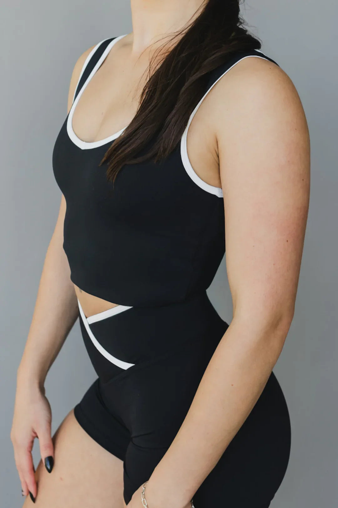 Woman wearing black athletic crop top and high-waisted shorts with white trim