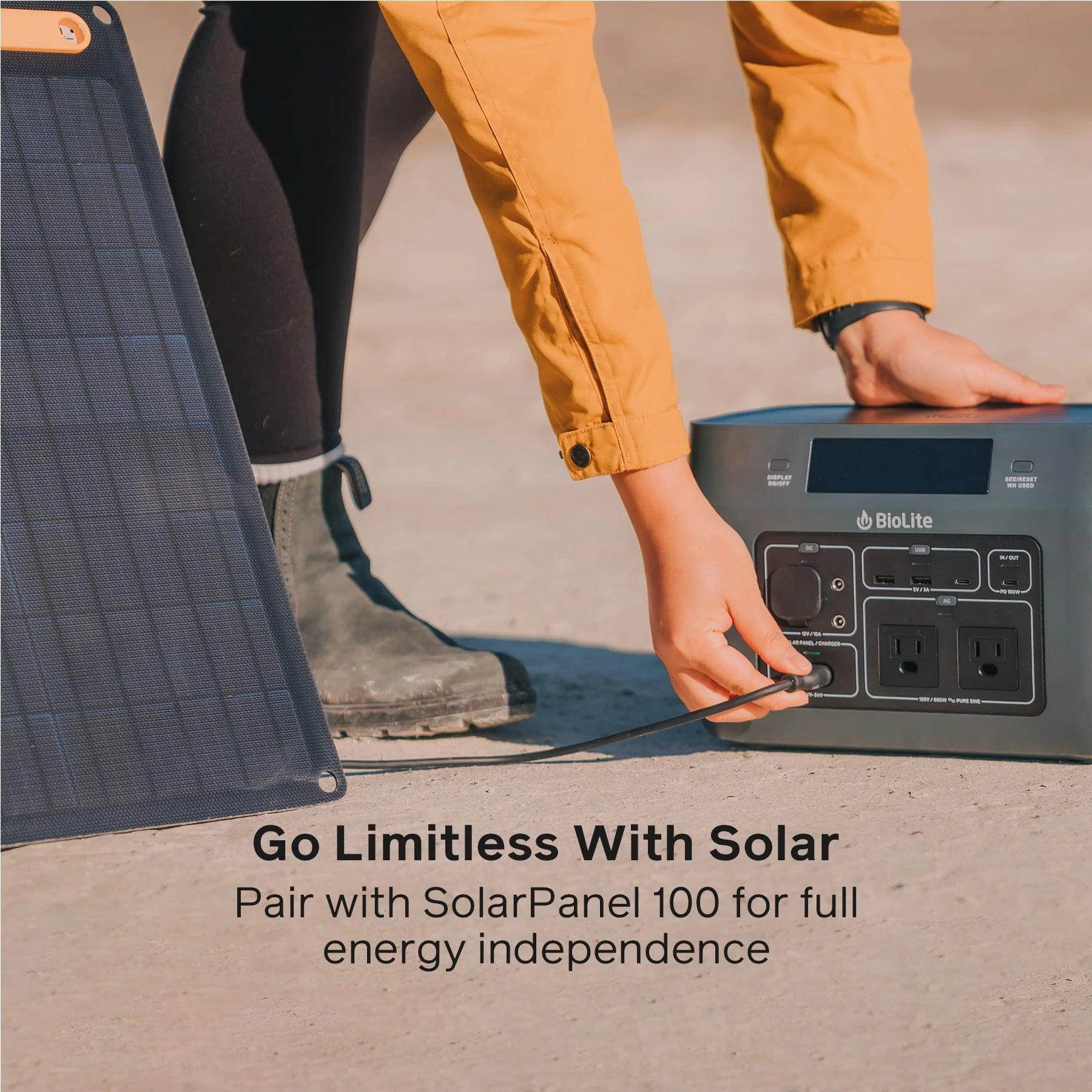 Person connecting Biolite BaseCharge 600 portable power station to solar panel outdoors
