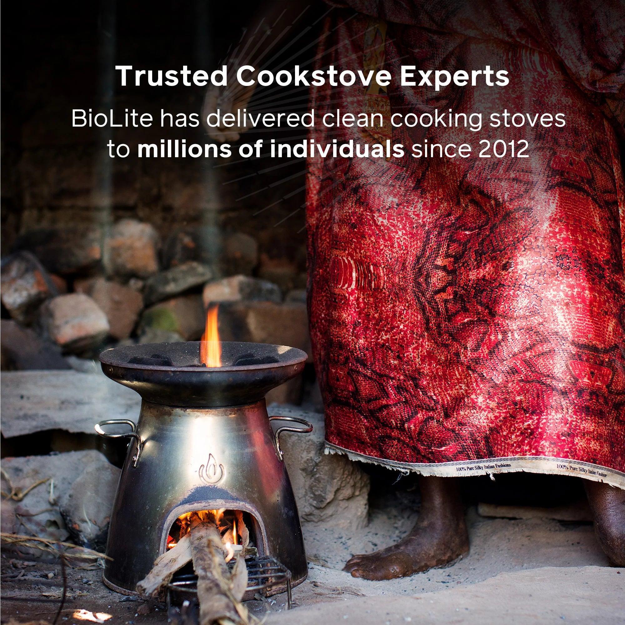 BioLite CampStove burning wood indoors beside person in red patterned clothing, stone background