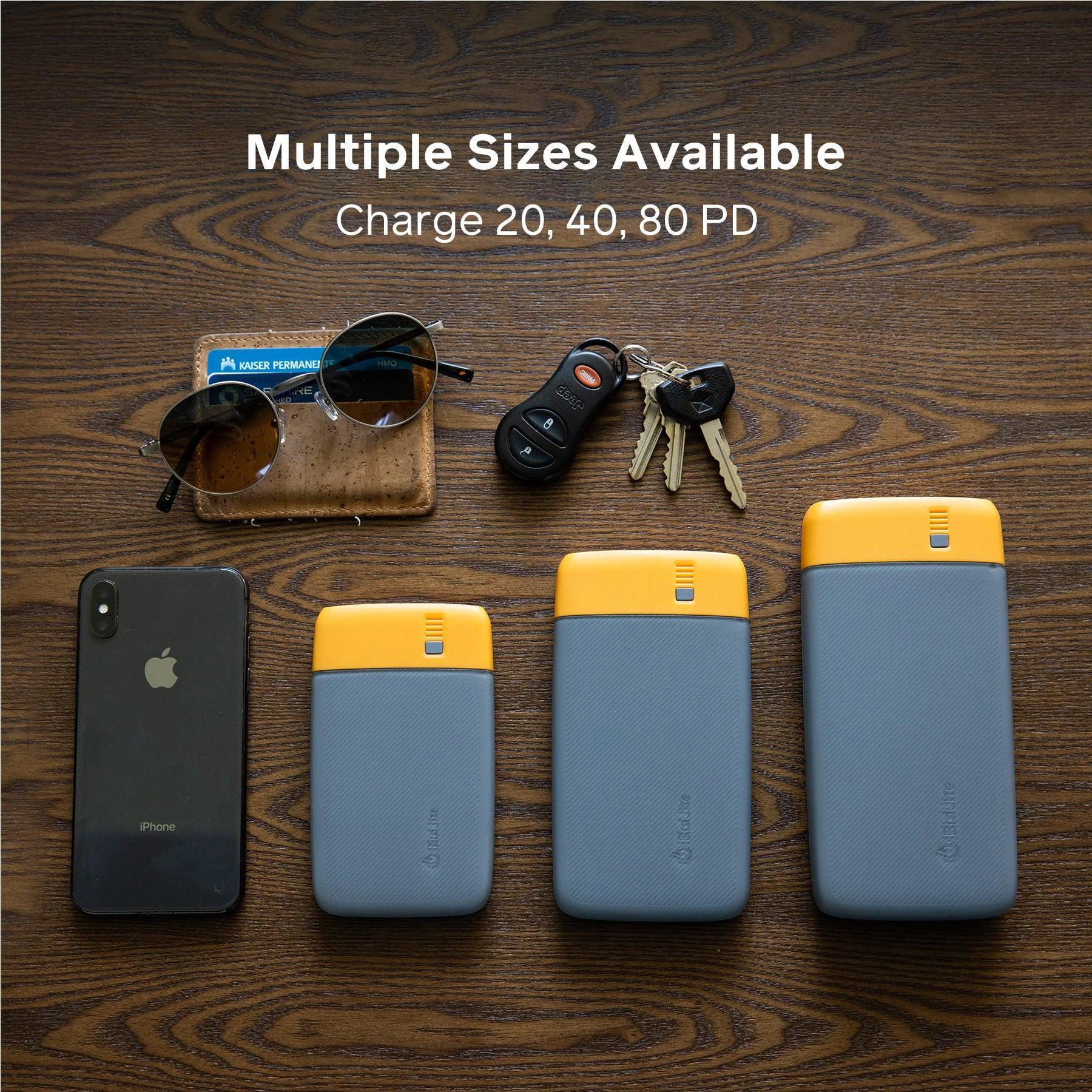 Three BioLite Charge PD power banks in different sizes on a wooden table with keys, sunglasses, wallet, and iPhone.