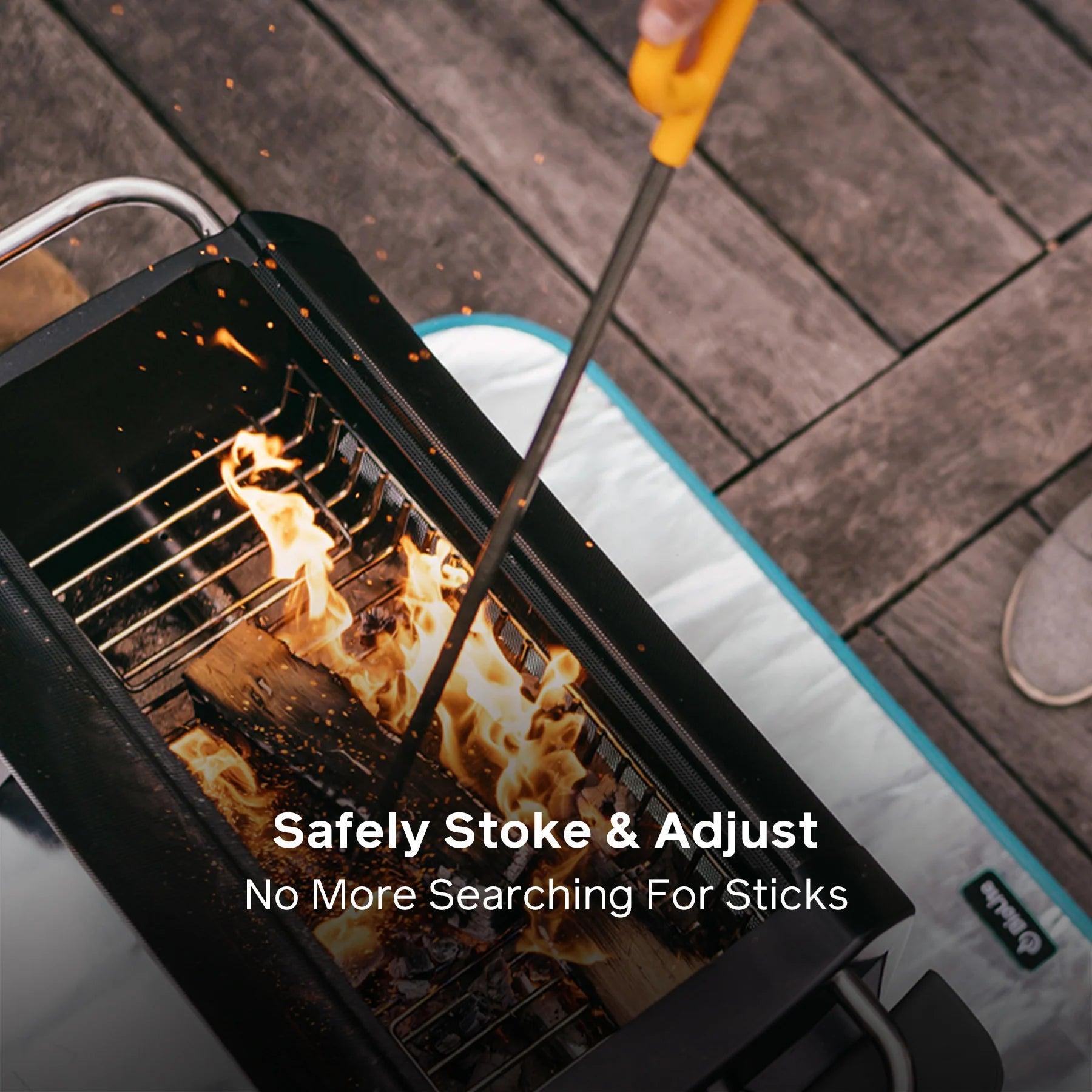 Person using fire poker to stoke flames in BioLite FirePit on wooden deck outdoors