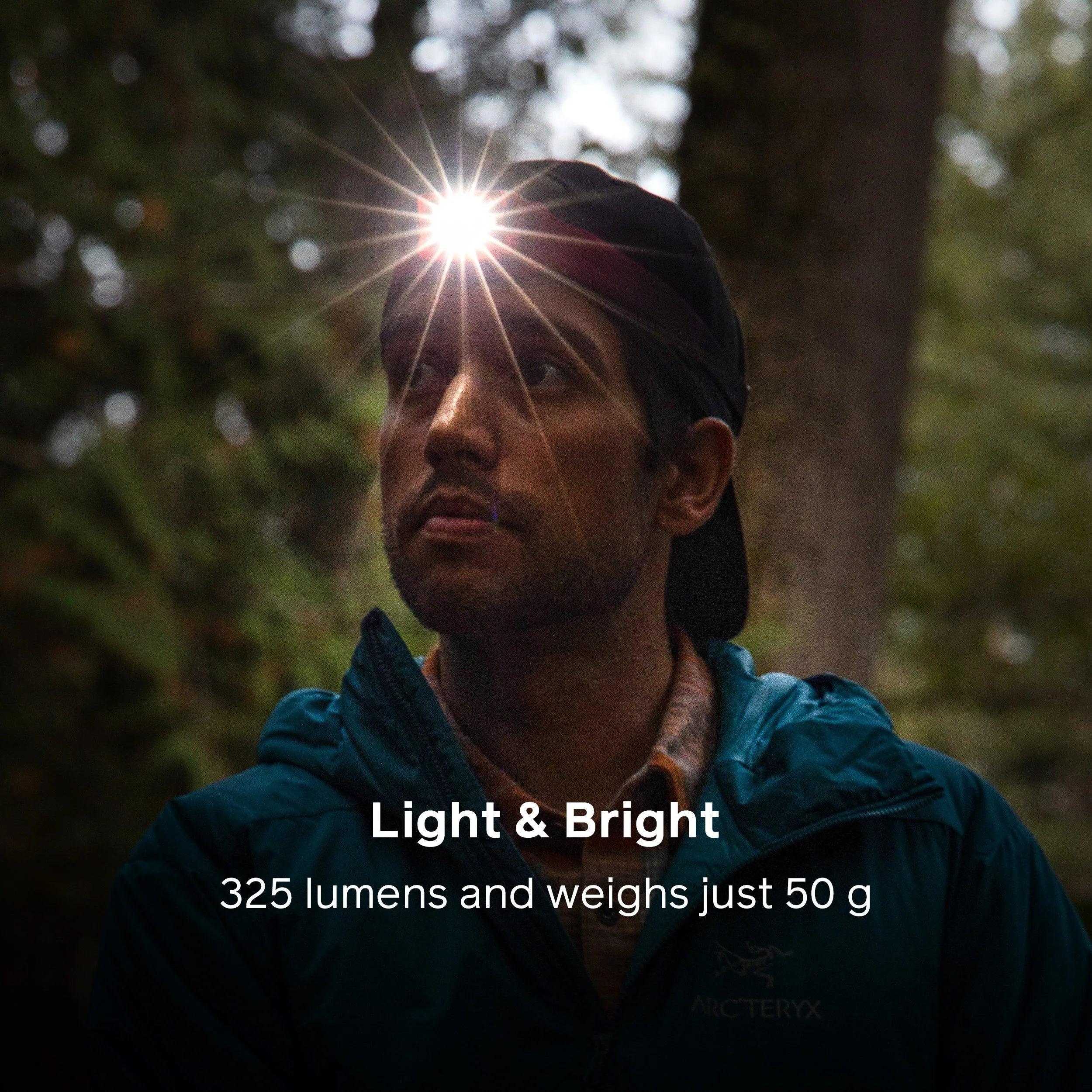 Man wearing a Biolite headlamp 325 lumens in a forest, outdoor gear visible.