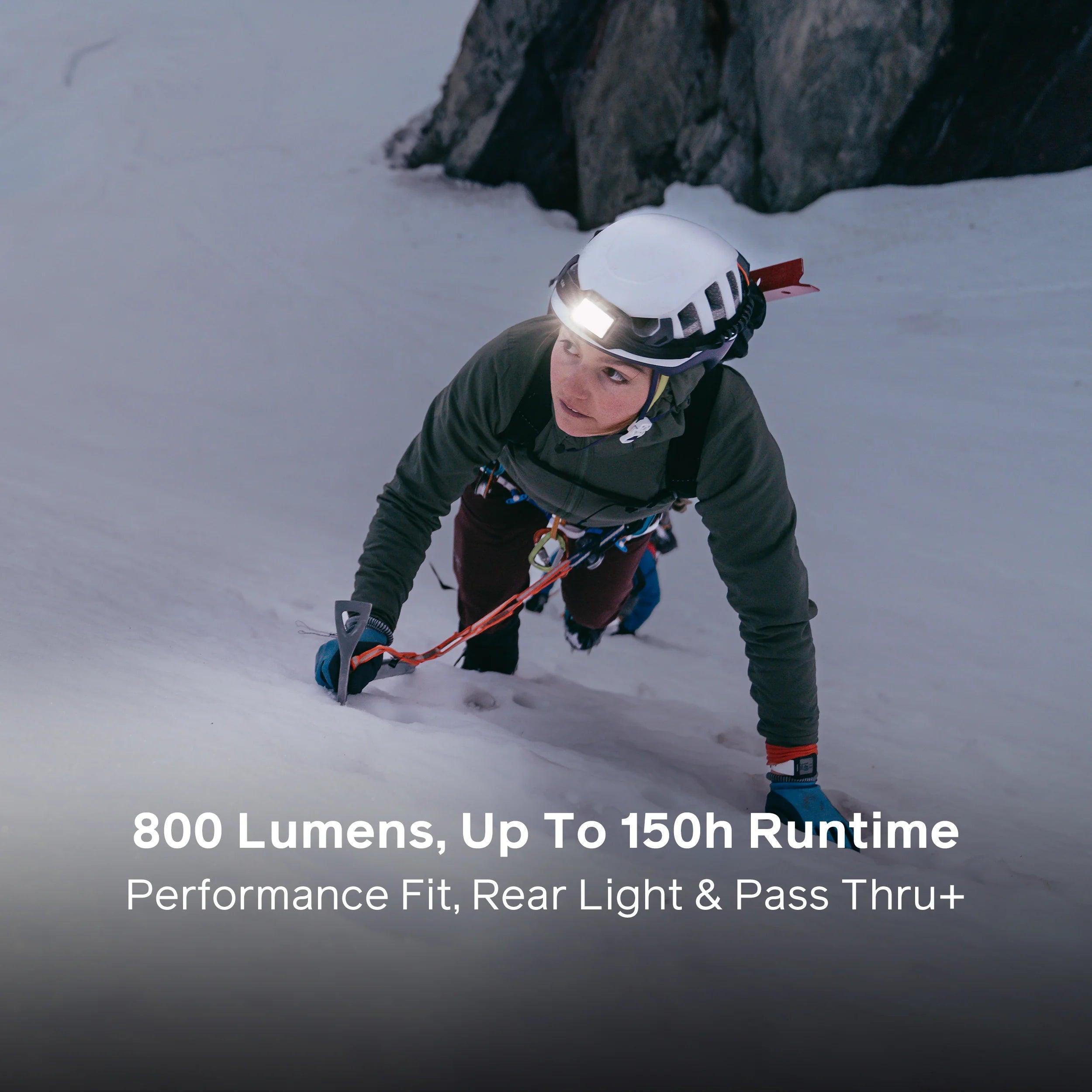 Climber on snowy mountain wearing headlamp and helmet, using ice axe for outdoor adventure