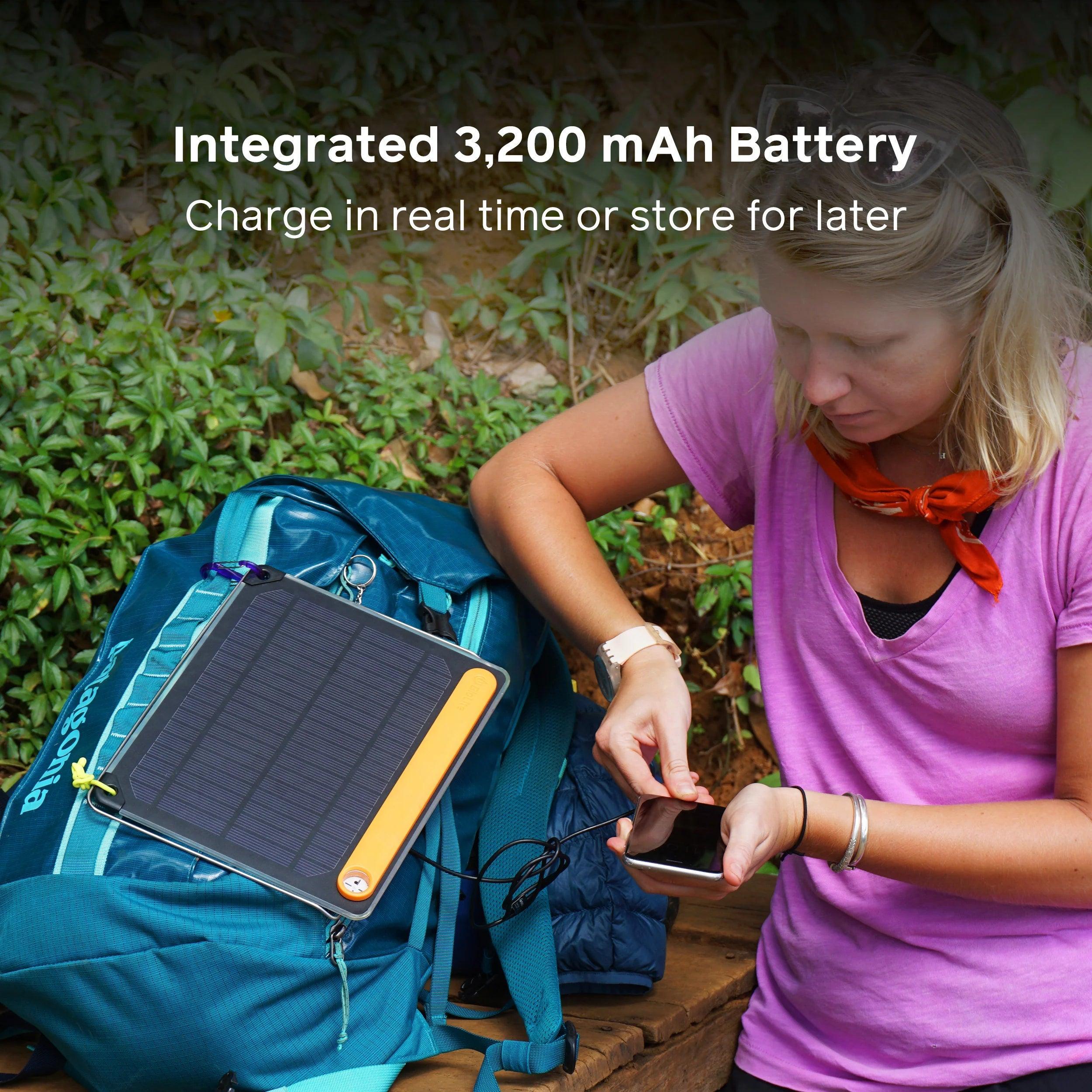 Woman charging phone with BioLite SolarPanel 5 attached to blue backpack outdoors