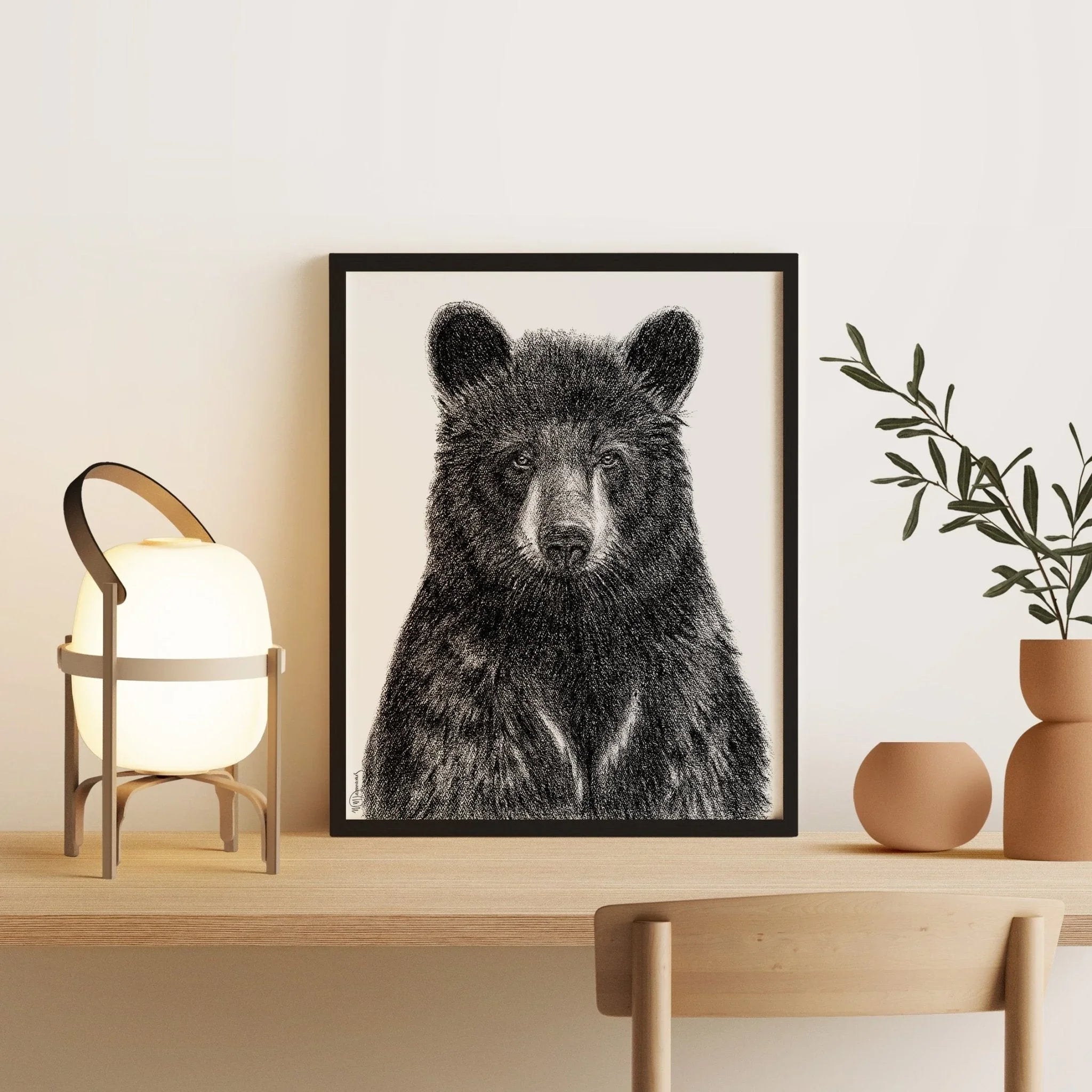 Black bear portrait art print on desk with modern lamp, plant, and pottery decor