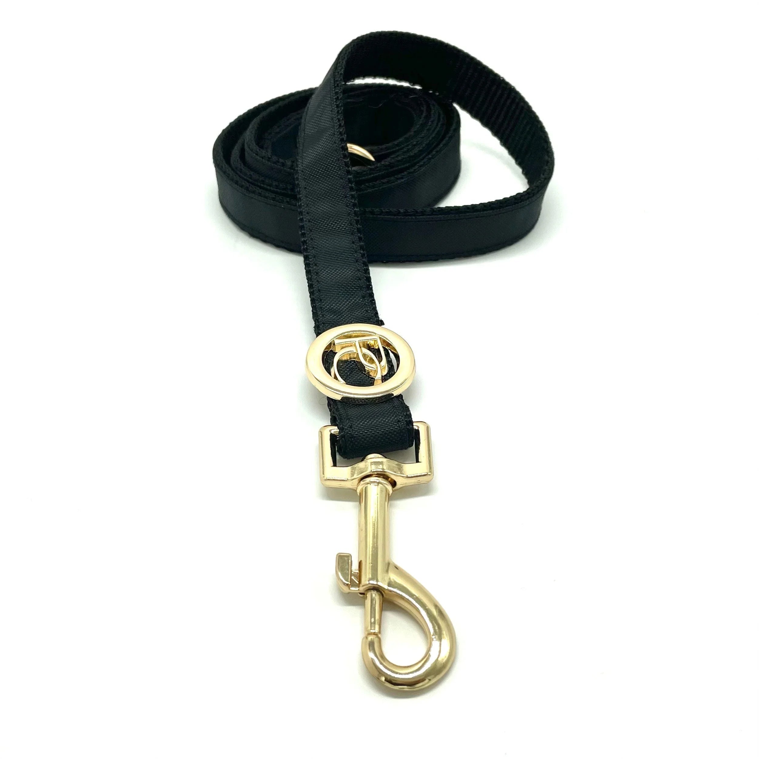 Black dog leash with gold metal clasp and decorative gold ring on white background
