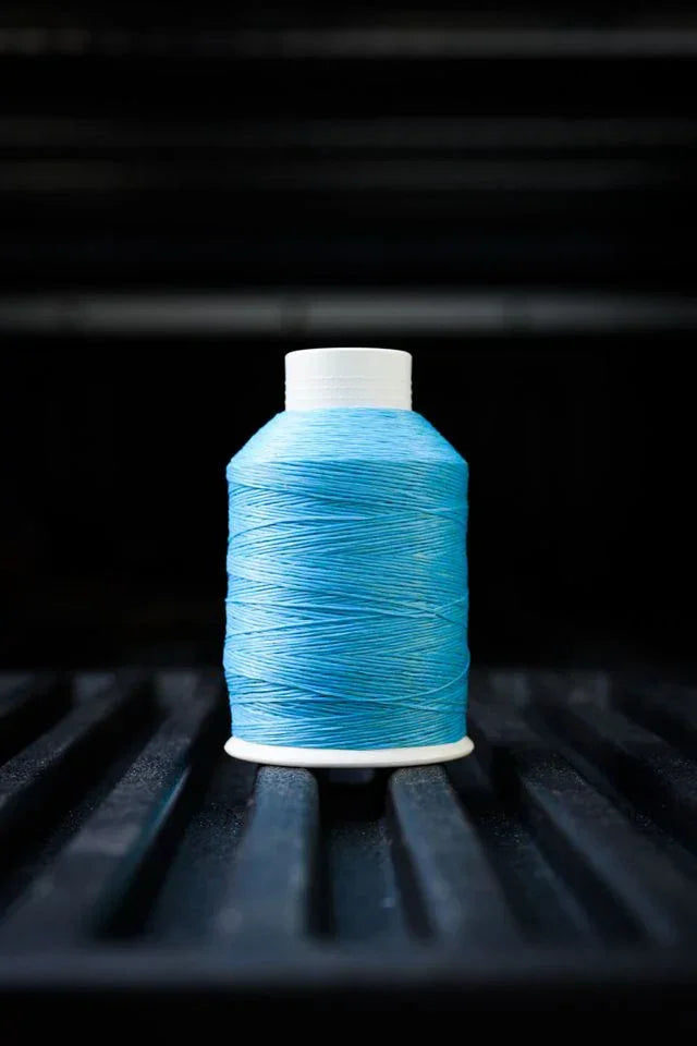 Robin blue polyester sewing thread spool on dark ridged background