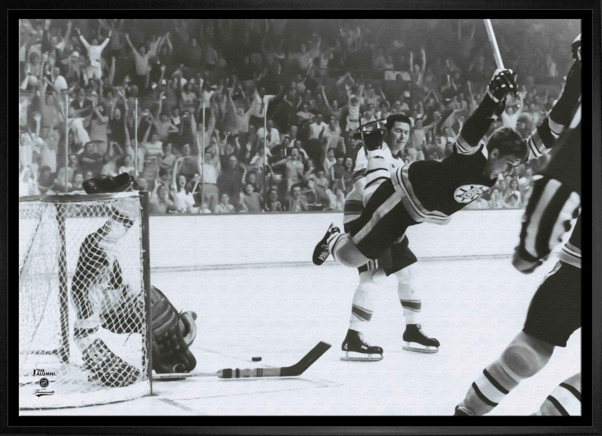 Black and white photo of a Boston Bruins hockey player mid-air celebrating a goal, cheering crowd.