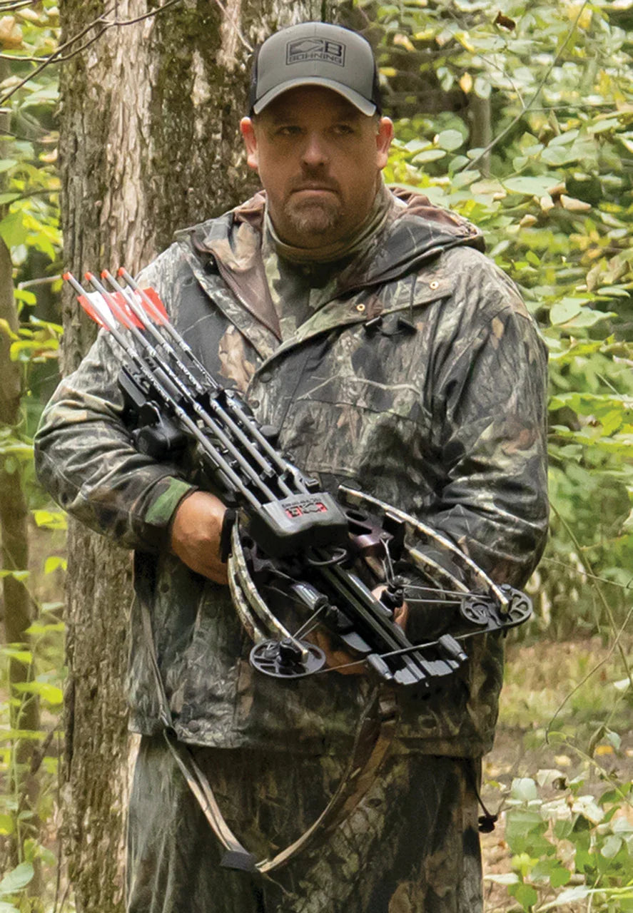 Hunter in camouflage holding a crossbow in a forest setting