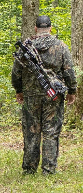 Hunter in camouflage suit carrying crossbow in forest wilderness