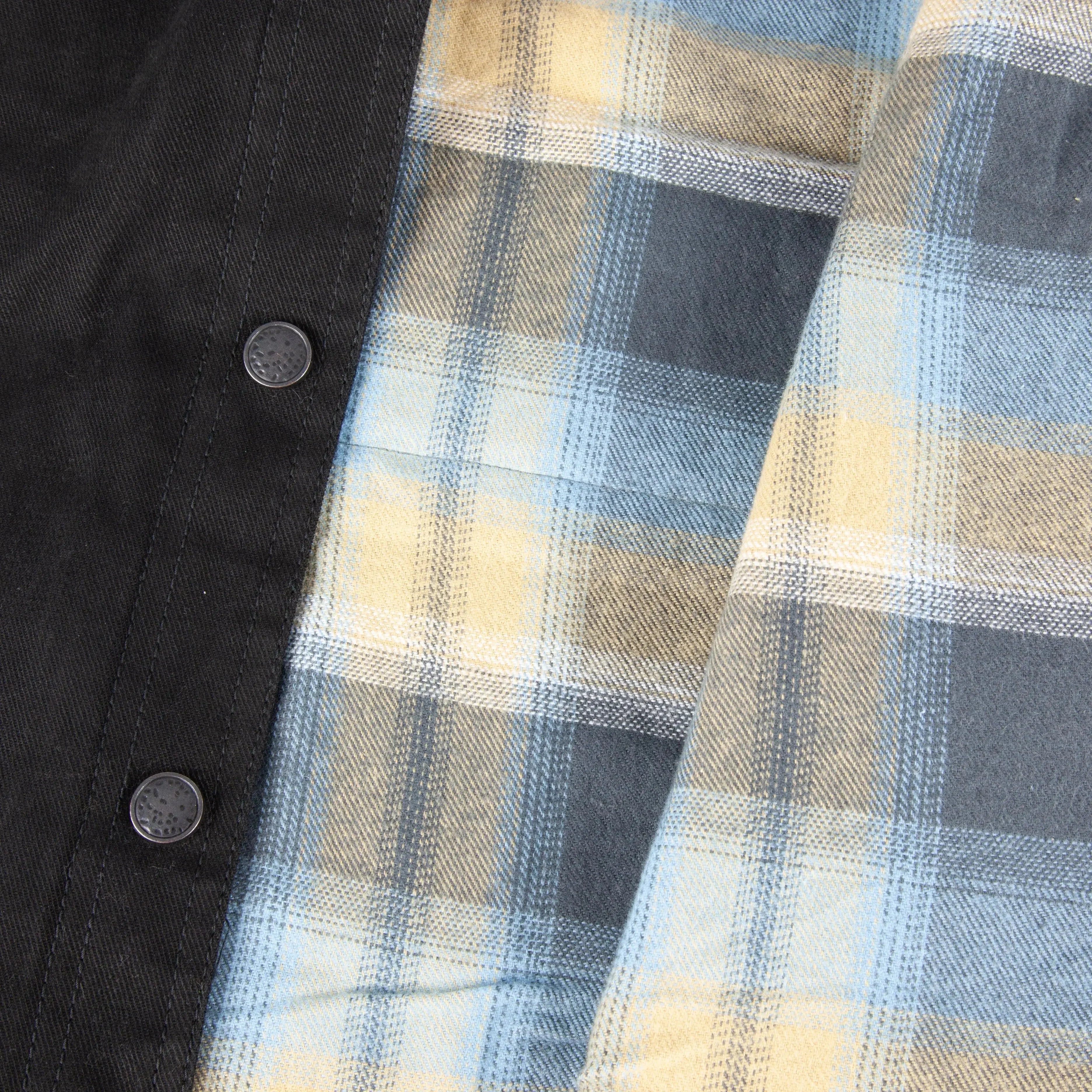 Close-up of black fabric with metal snap buttons and yellow-blue plaid lining on heated jacket