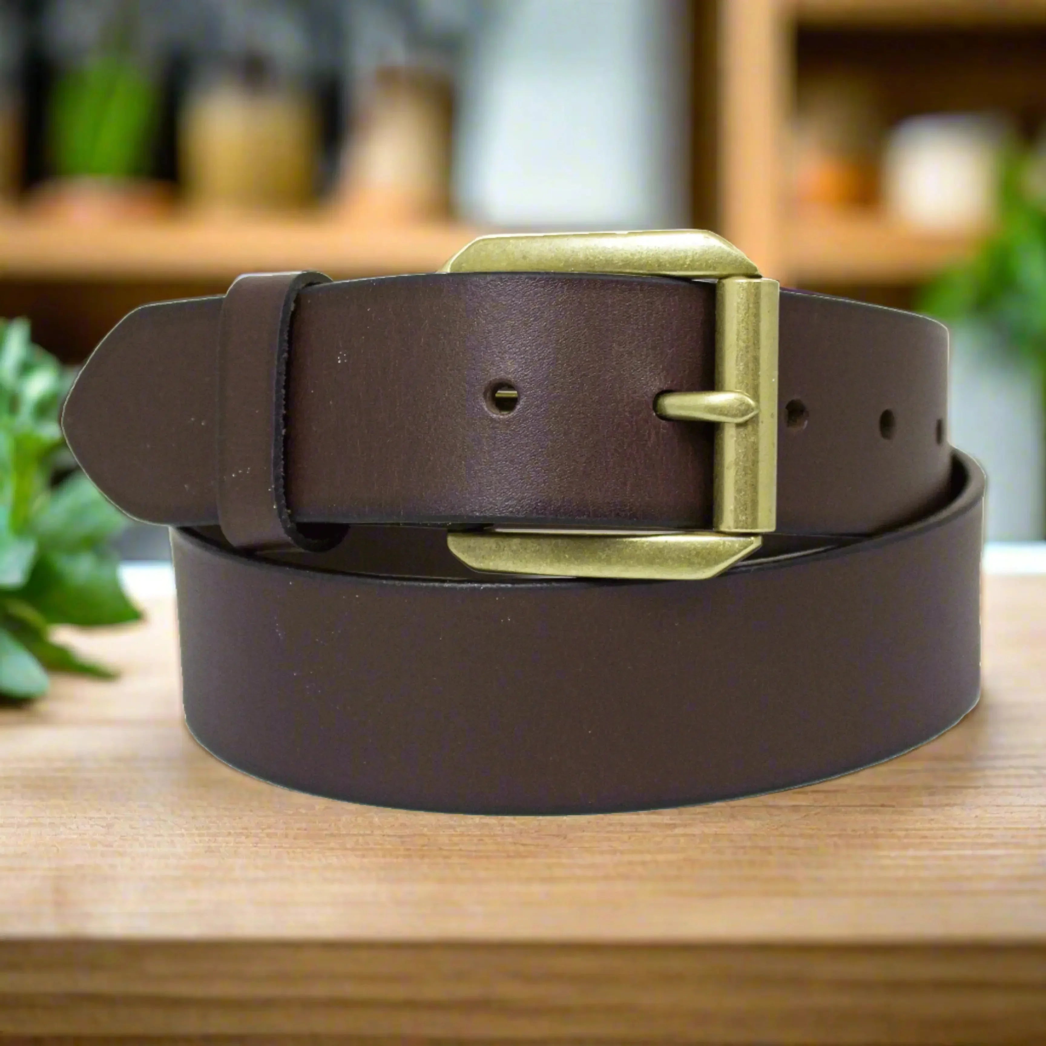 Men's brown leather belt with gold removable buckle on wooden surface