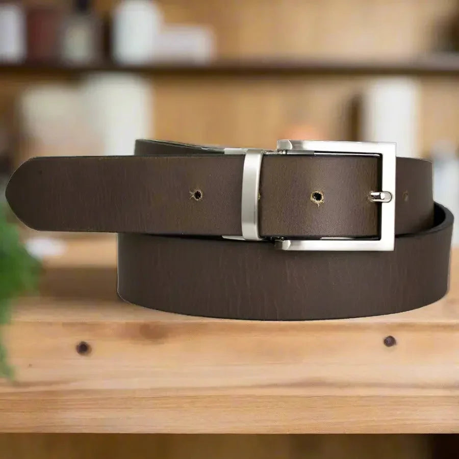 Men's brown reversible leather belt with silver buckle on wooden table