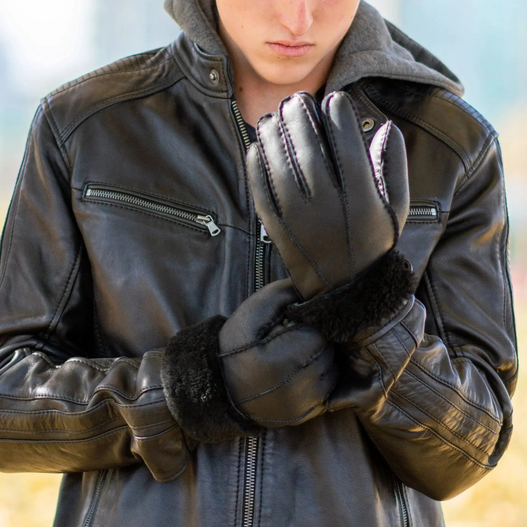 Man wearing black shearling leather gloves and leather jacket outdoors