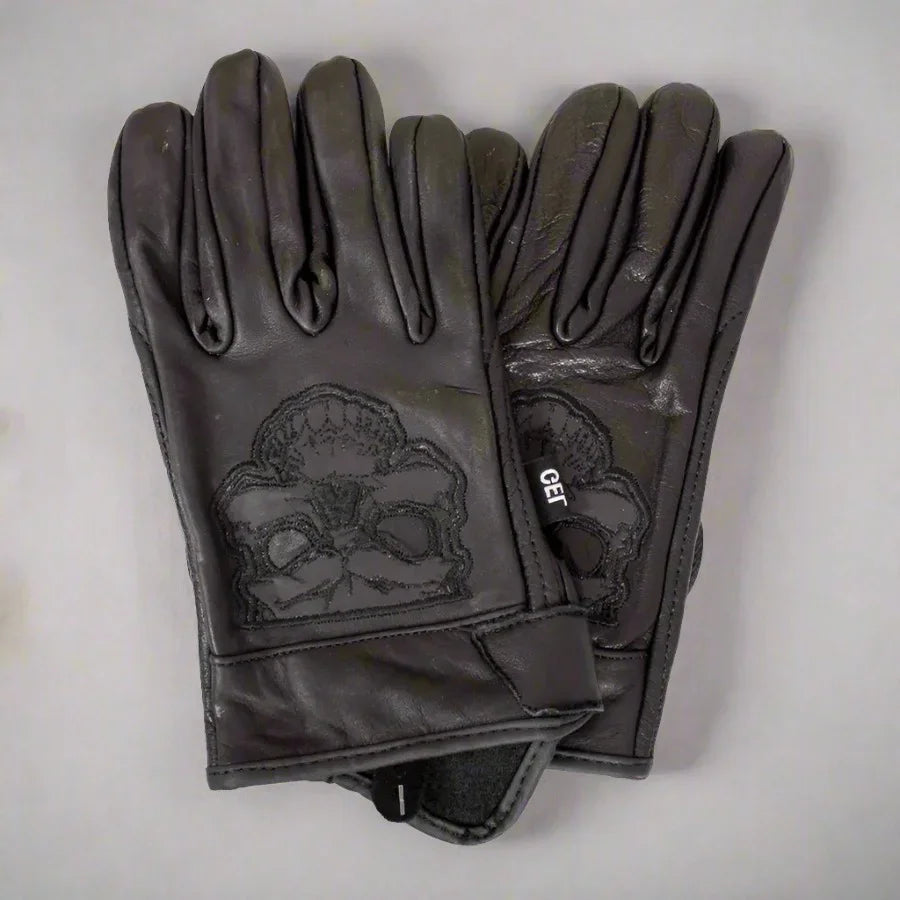 Men's black leather motorcycle gloves with reflective skull design on grey background