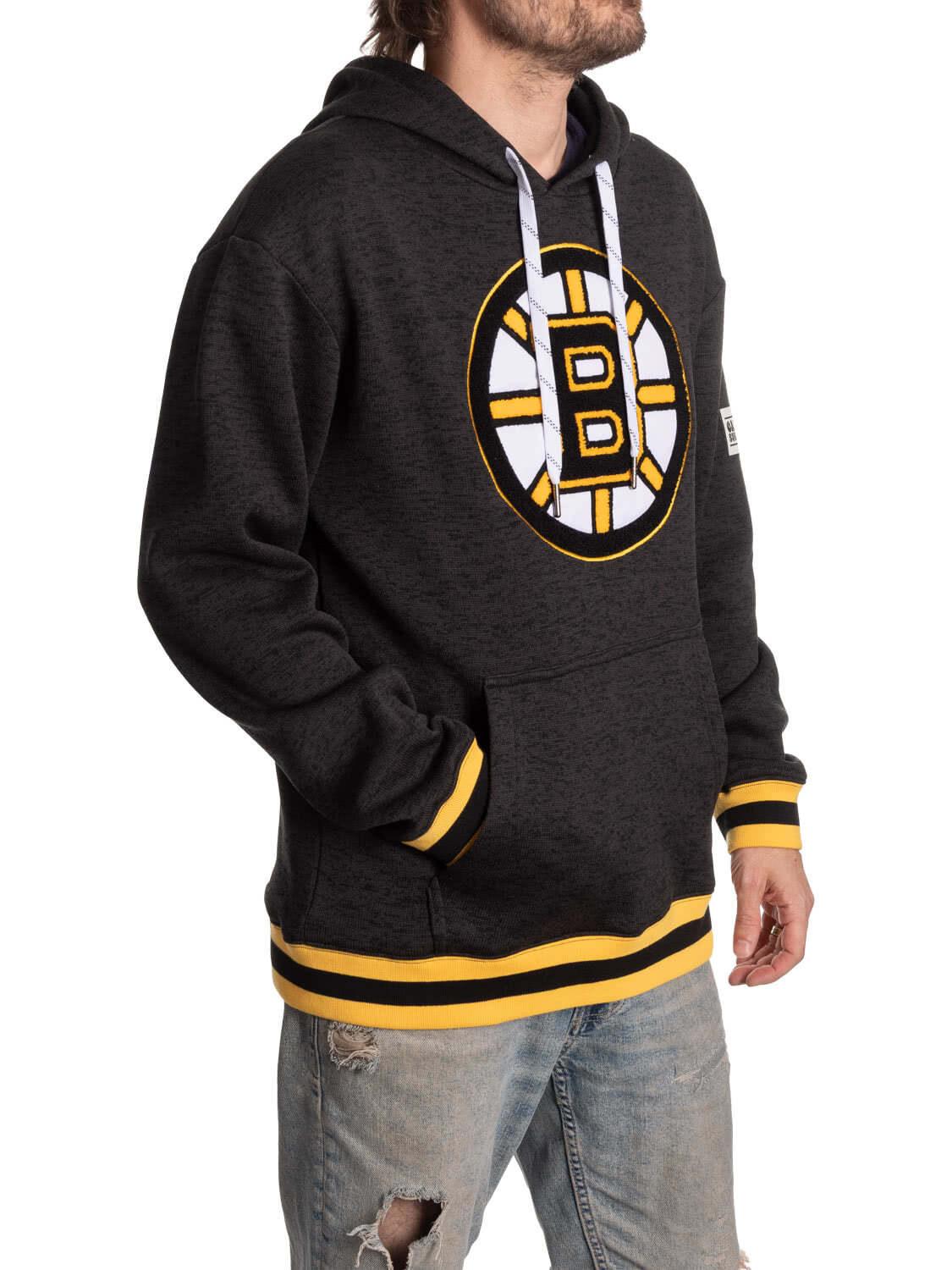Boston Bruins black hoodie with yellow logo, worn by man in ripped jeans