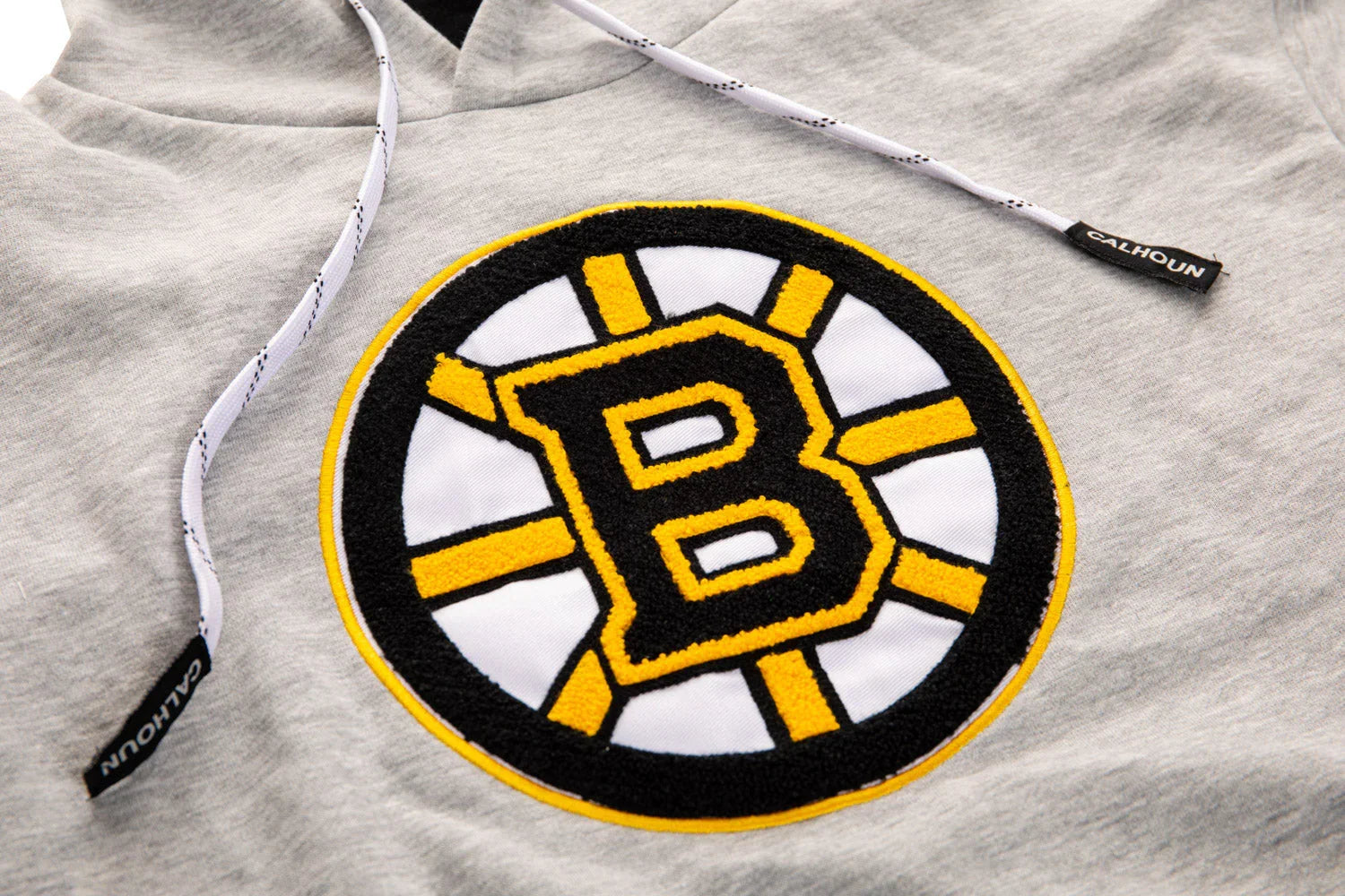 Close-up of Boston Bruins hockey logo on grey Calhoun hoodie drawstring detail