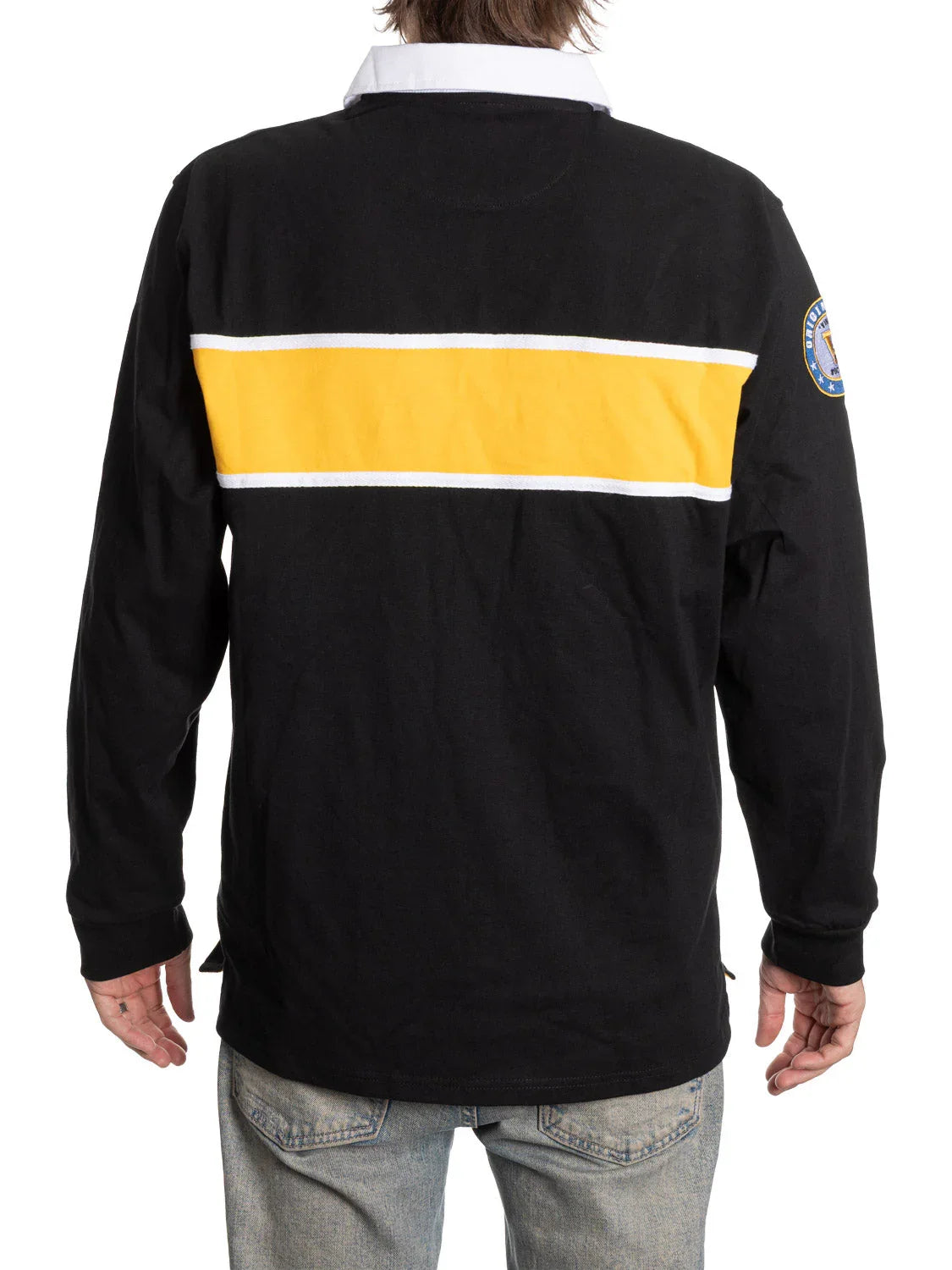 Back view of black rugby shirt with yellow and white stripe, patch on sleeve, and jeans