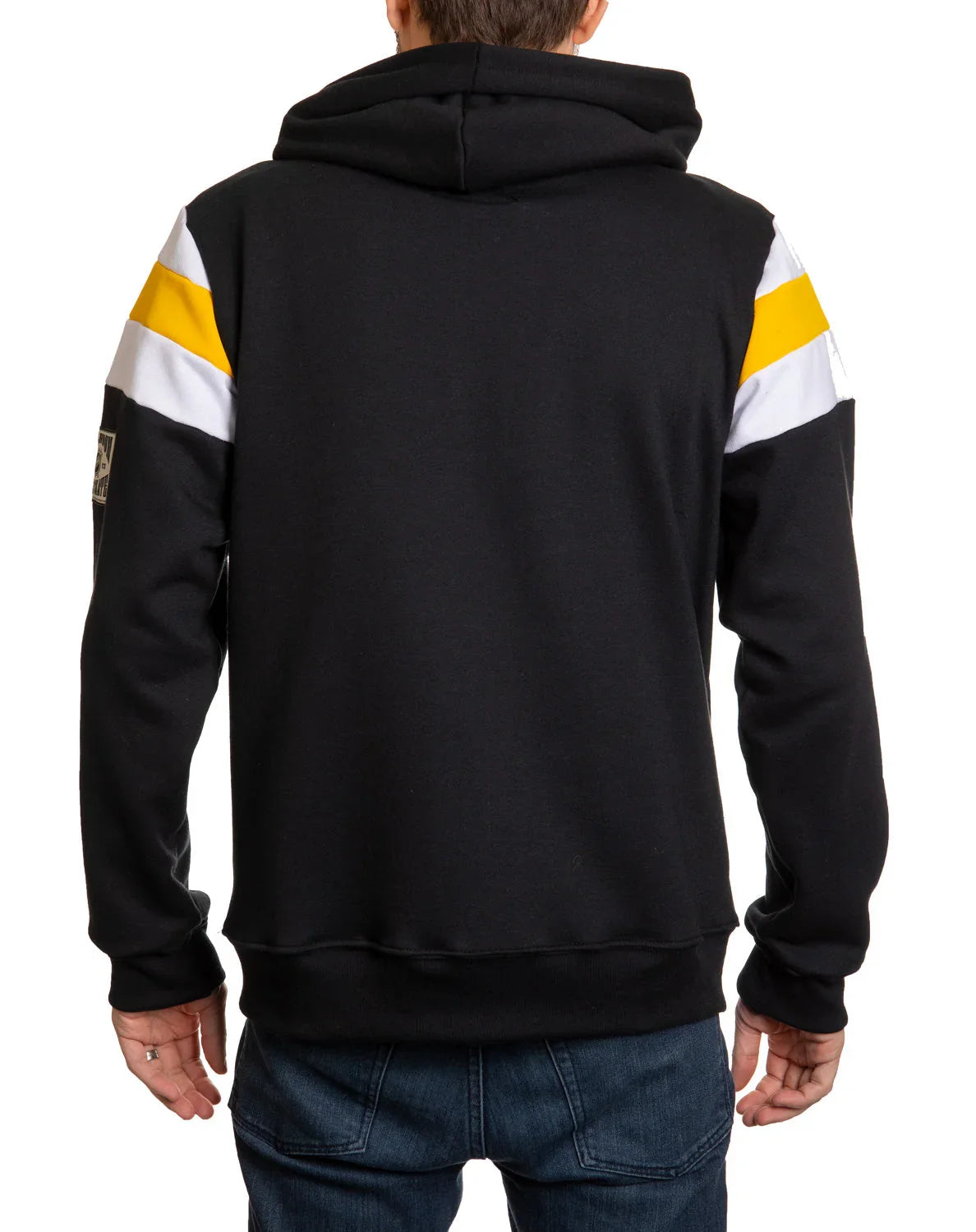 Back view of person wearing black hoodie with yellow and white sleeve stripes, blue jeans