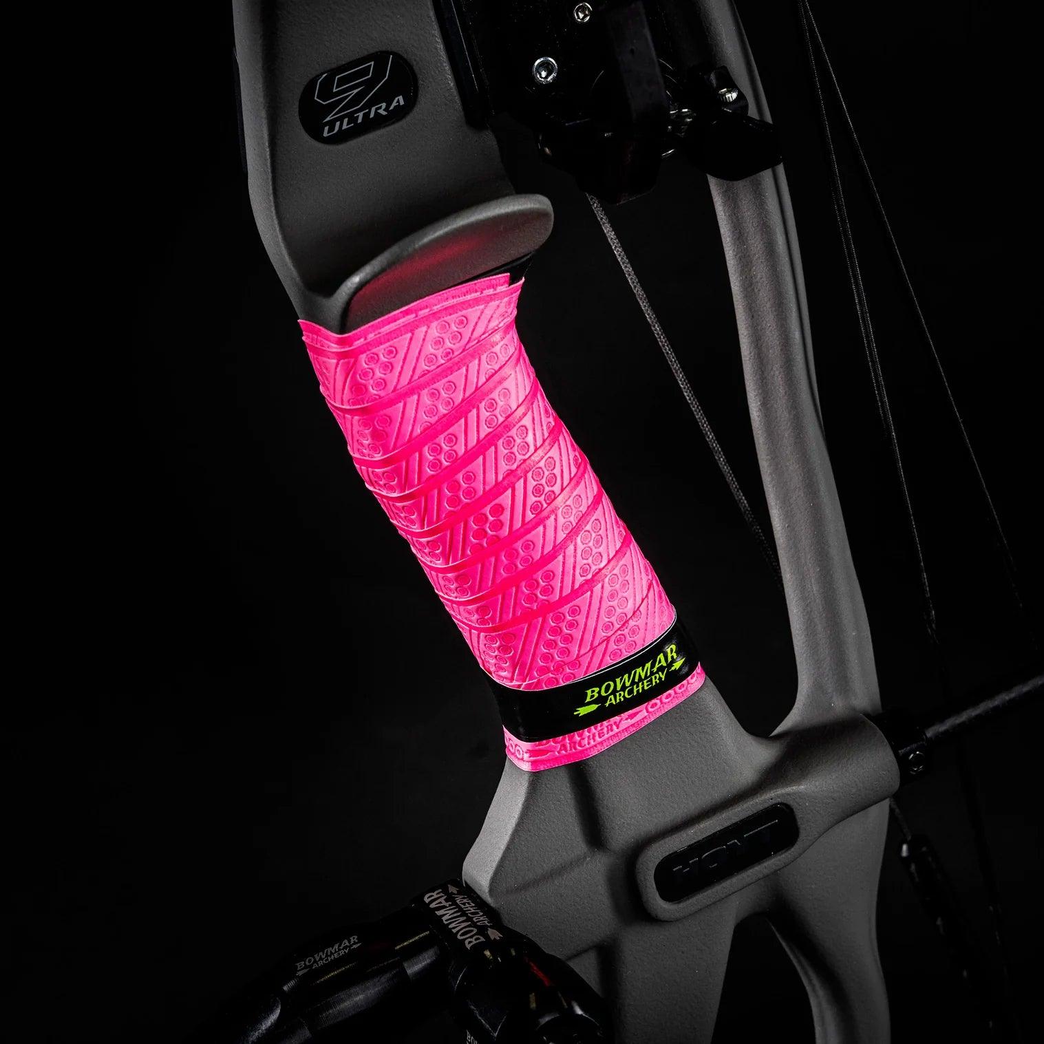 Matte compound bow with bright pink Bowmar Archery grip wrap, closeup on black background