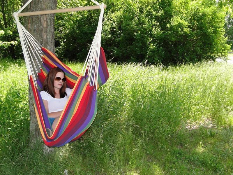 Woman relaxing in a colorful Brazilian hammock chair outdoors on a sunny day