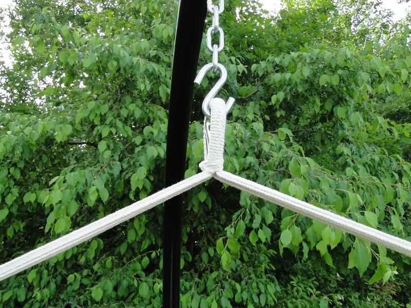 Hammock chair stand hook and rope closeup outdoors with green leafy background