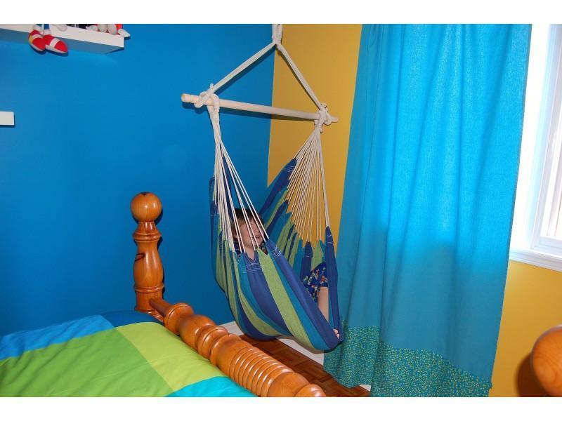 Child relaxing in a striped Brazilian hammock chair in a colorful bedroom
