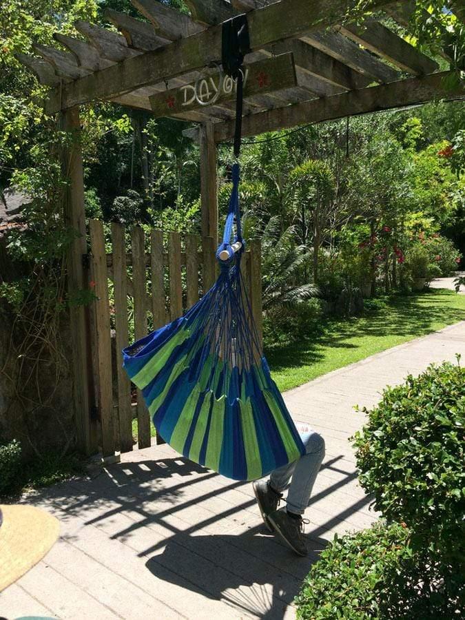 Blue and green Brazilian hammock chair hanging outdoors in a sunny garden