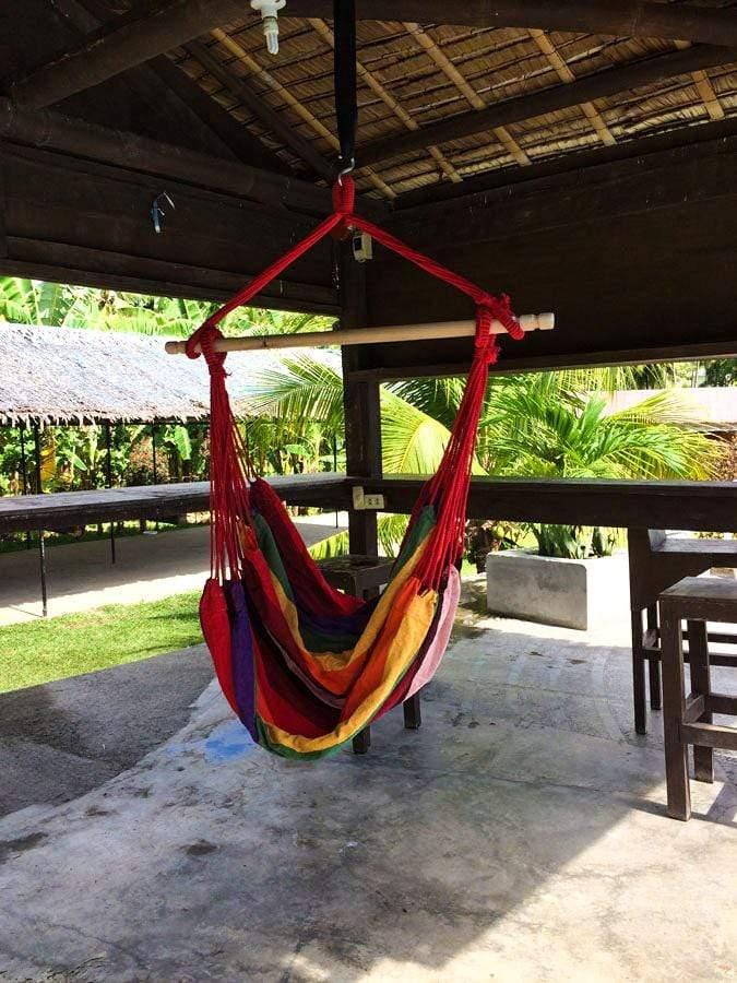 Brazilian hammock chair in vibrant colors hanging in a shaded outdoor patio