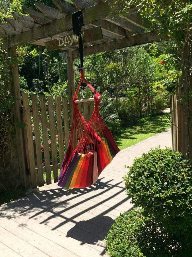 Brazilian hammock chair with hot colors hanging in a garden under a wooden pergola