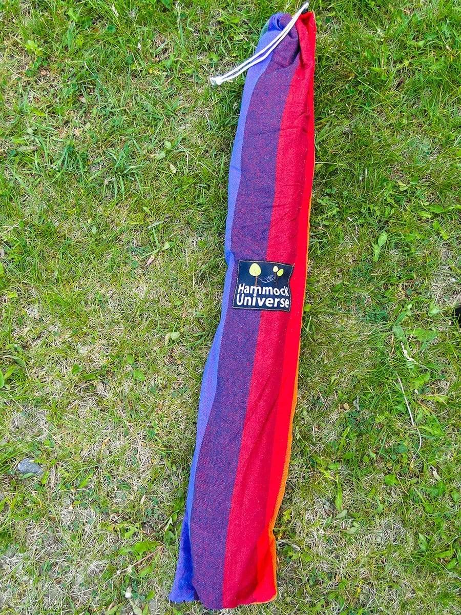 Brazilian hammock chair in colorful bag on green grass, Hammock Universe label visible