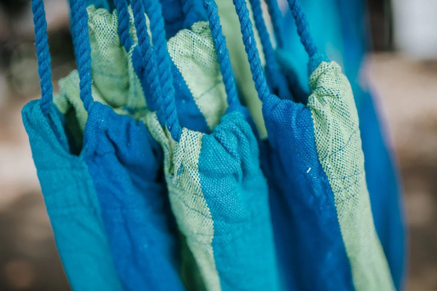Close-up of blue and light green woven fabric drawstring bags hanging together