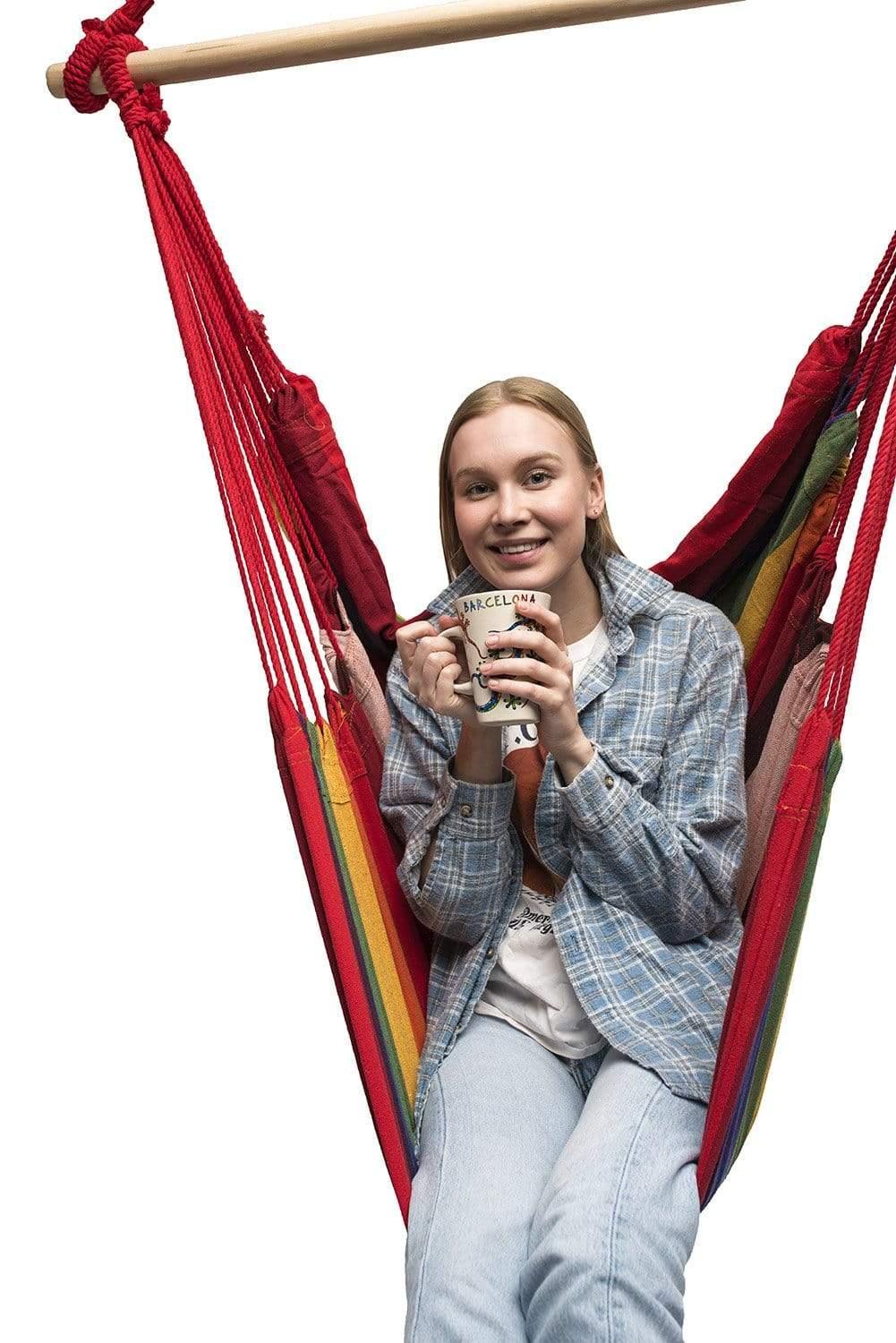 Smiling woman in a red striped Brazilian hammock chair holding a coffee mug on white background