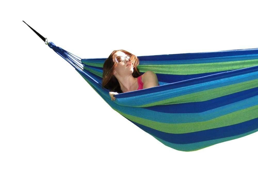 Woman relaxing in blue and green striped hammock on white background