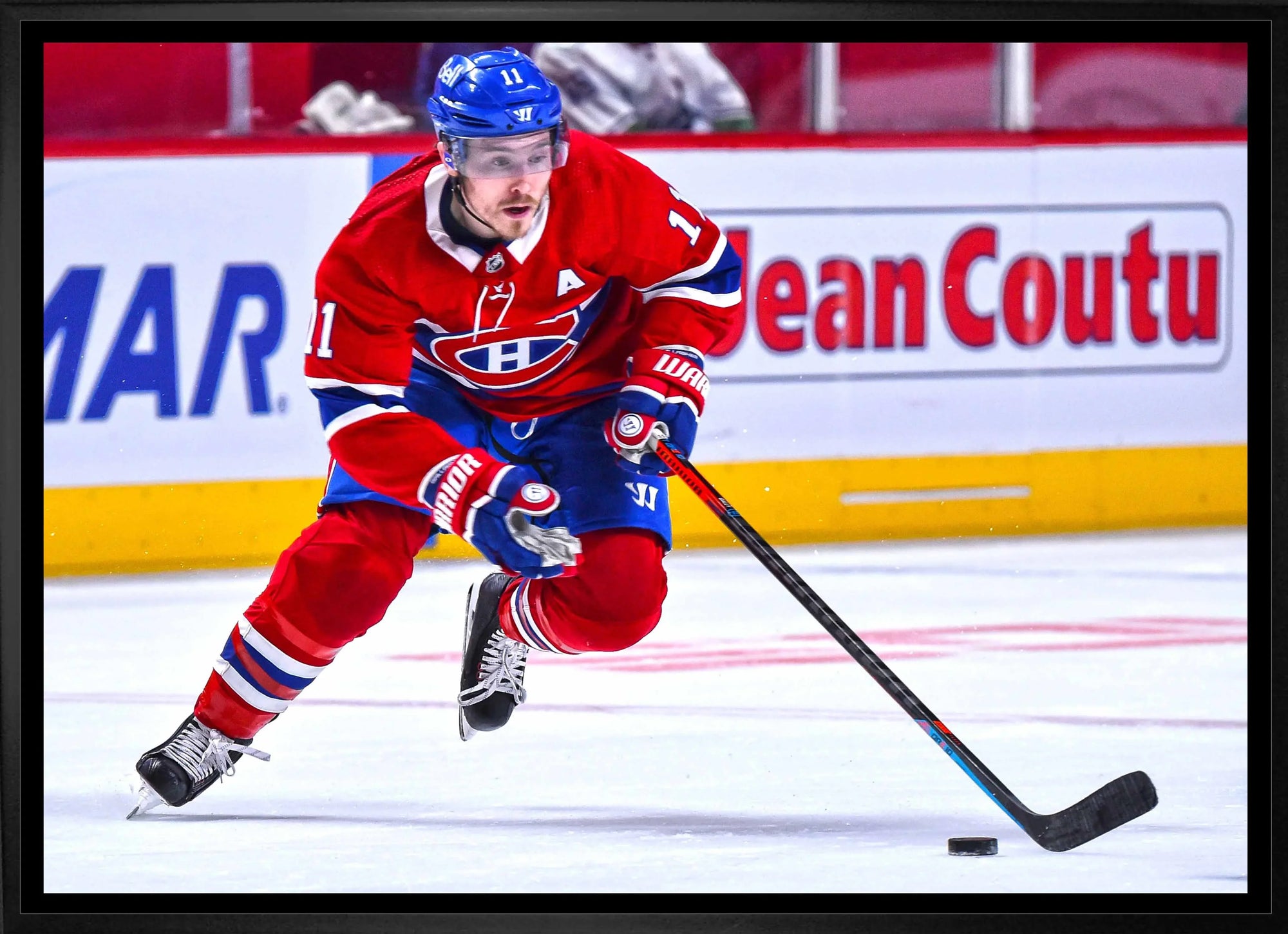 Montreal Canadiens hockey player in red jersey skating and controlling puck on ice rink