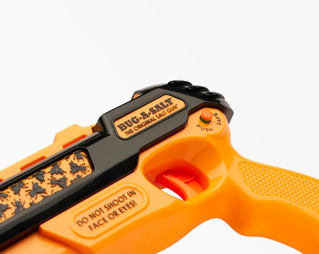 Close-up of a yellow Bug-A-Salt insect gun with safety switch and fly illustrations