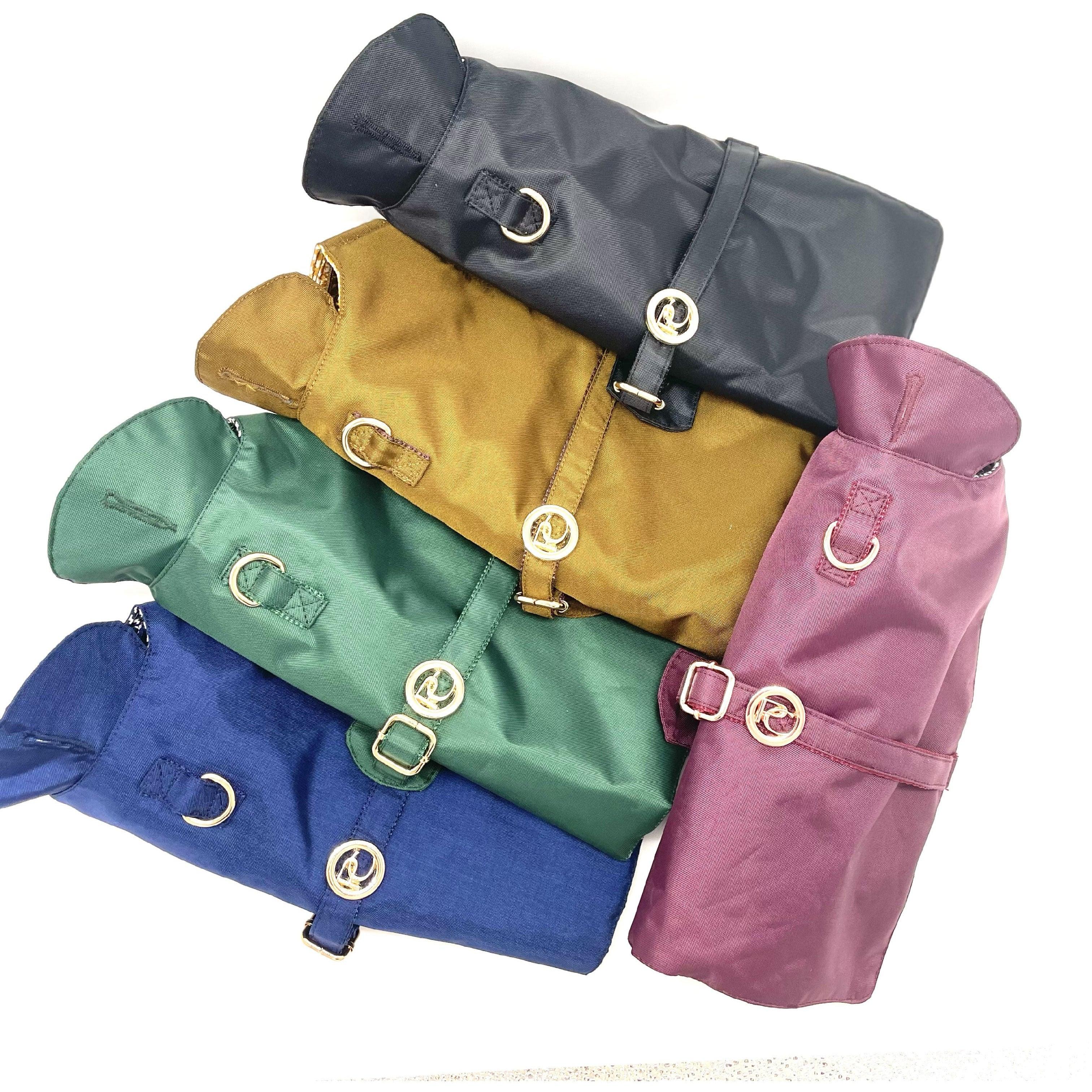 Colorful dog jackets with buckles and rings stacked on white background