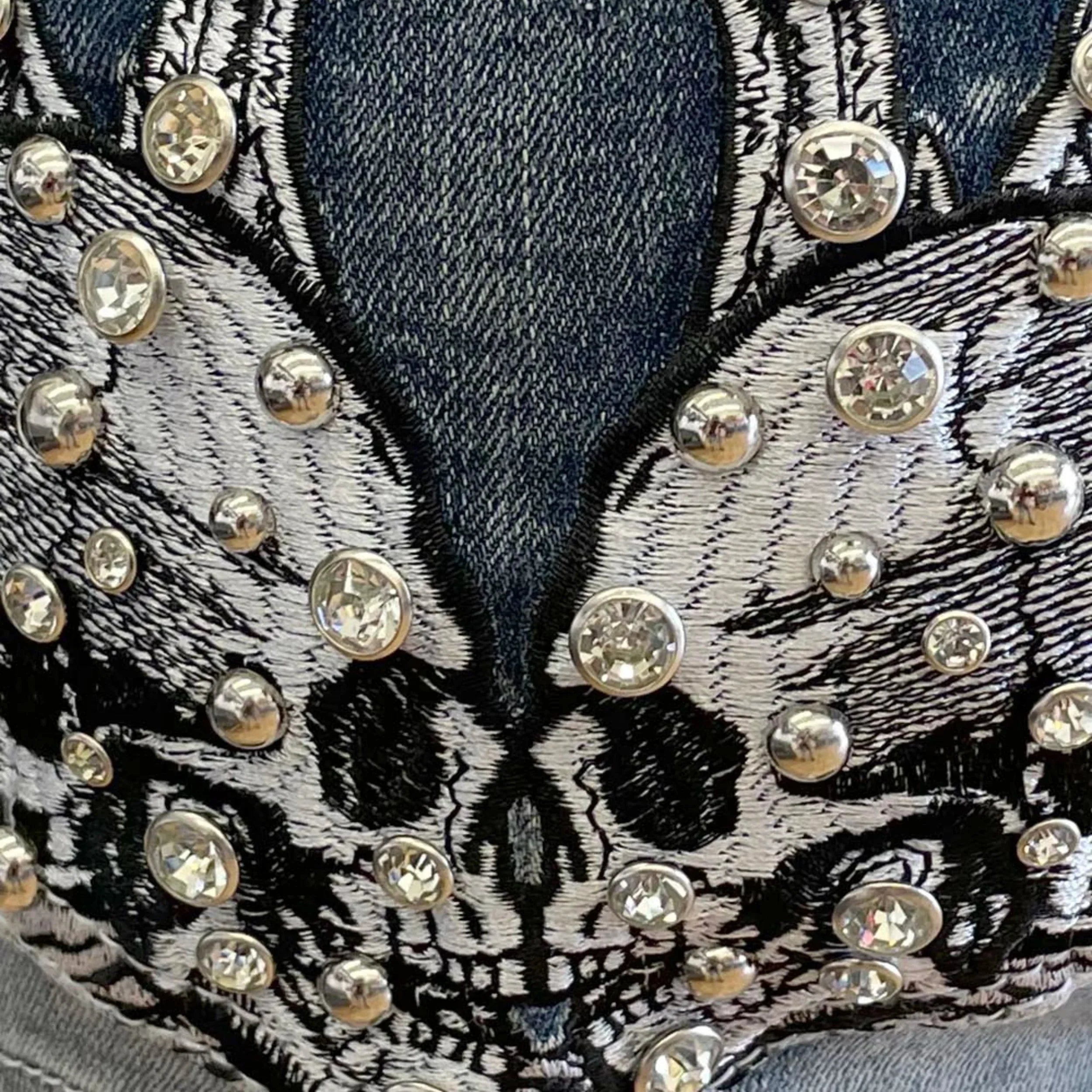 Close-up of denim pocket with embroidered skull design and rhinestone embellishments