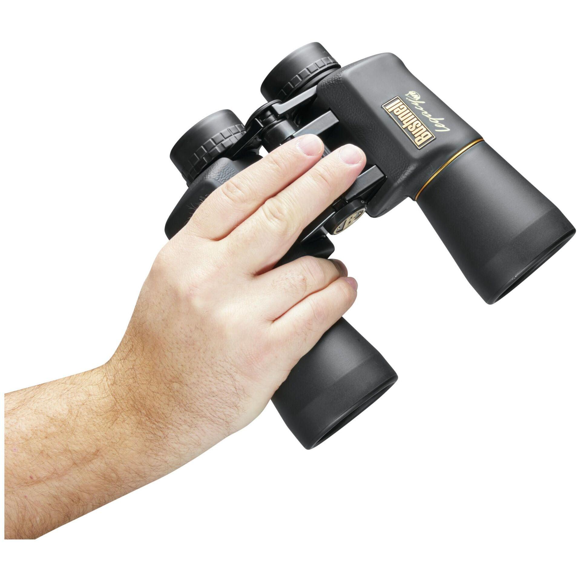 Hand holding Bushnell Legacy WP 10x50 binoculars against white background