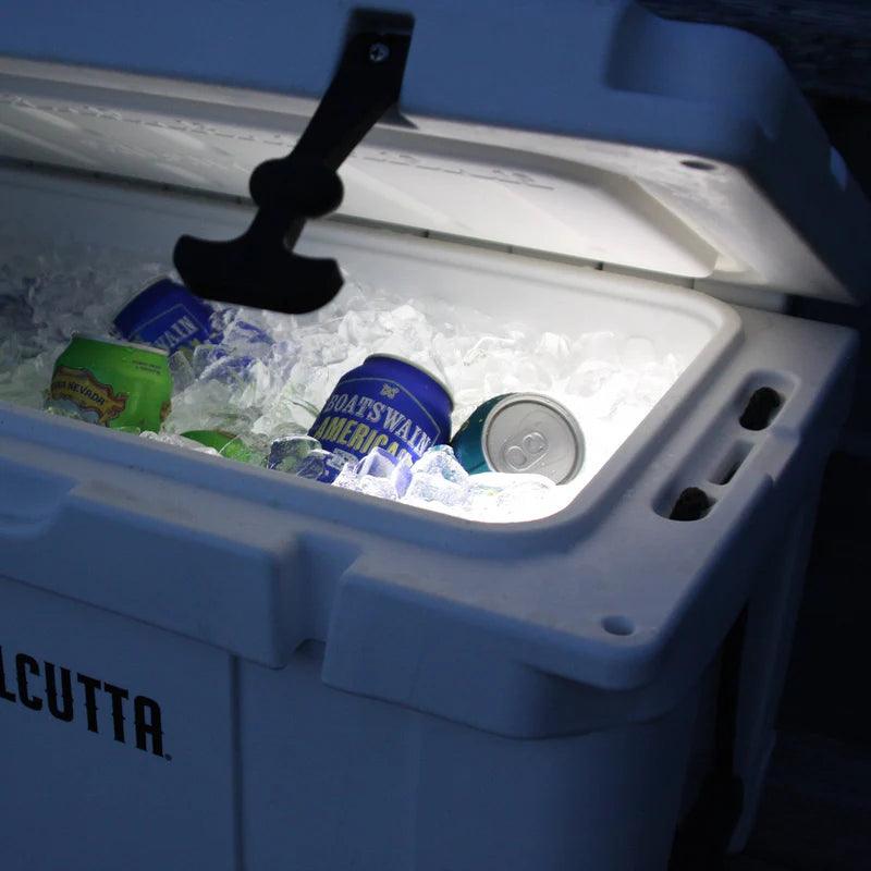 Lit cooler with ice and assorted beverage cans inside at night
